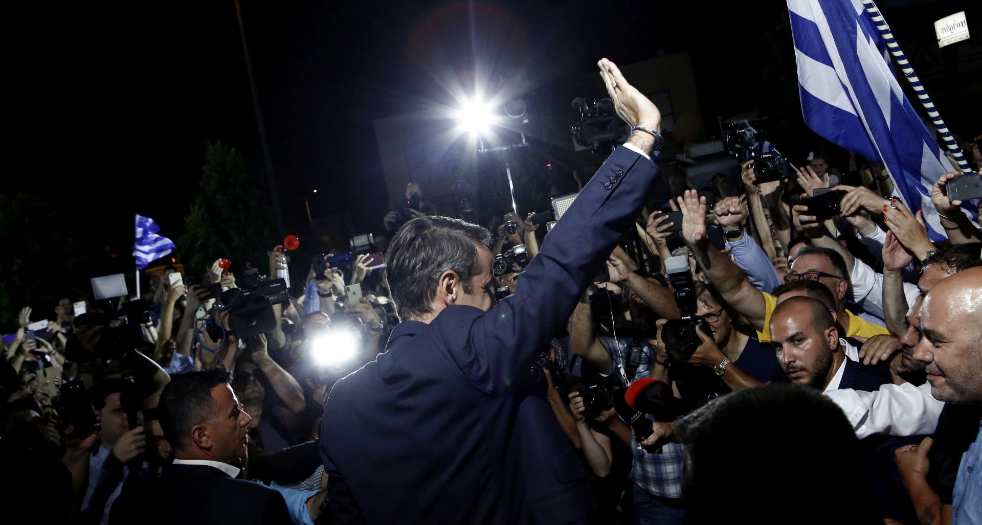 epa07702044 Leader of conservative New Democracy, Kyriakos Mitsotakis (C) waves to supporters after the announcement of the first results of the Greek general elections, at the headquarter's party, in Athens, Greece, 07 July 2019. The result (100 pct of sample) of the first exit polls for the 2019 general elections in Greece were released after the closing of the polls at 19:00 on Sunday. They indicate a victory by a substantial margin for New Democracy, which is seen getting an absolute majority in parliament.  EPA/YANNIS KOLESIDIS