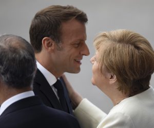 epa07716164 French President Emmanuel Macron (C) embraces German Chancellor Angela Merkel (R) as they attend the annual Bastille Day military parade on the Champs Elysees avenue in Paris, France, 14 July 2019 Bastille Day, the French National Day, is held annually on 14 July to commemorate the storming of the Bastille fortress in 1789.  EPA/IAN LANGSDON