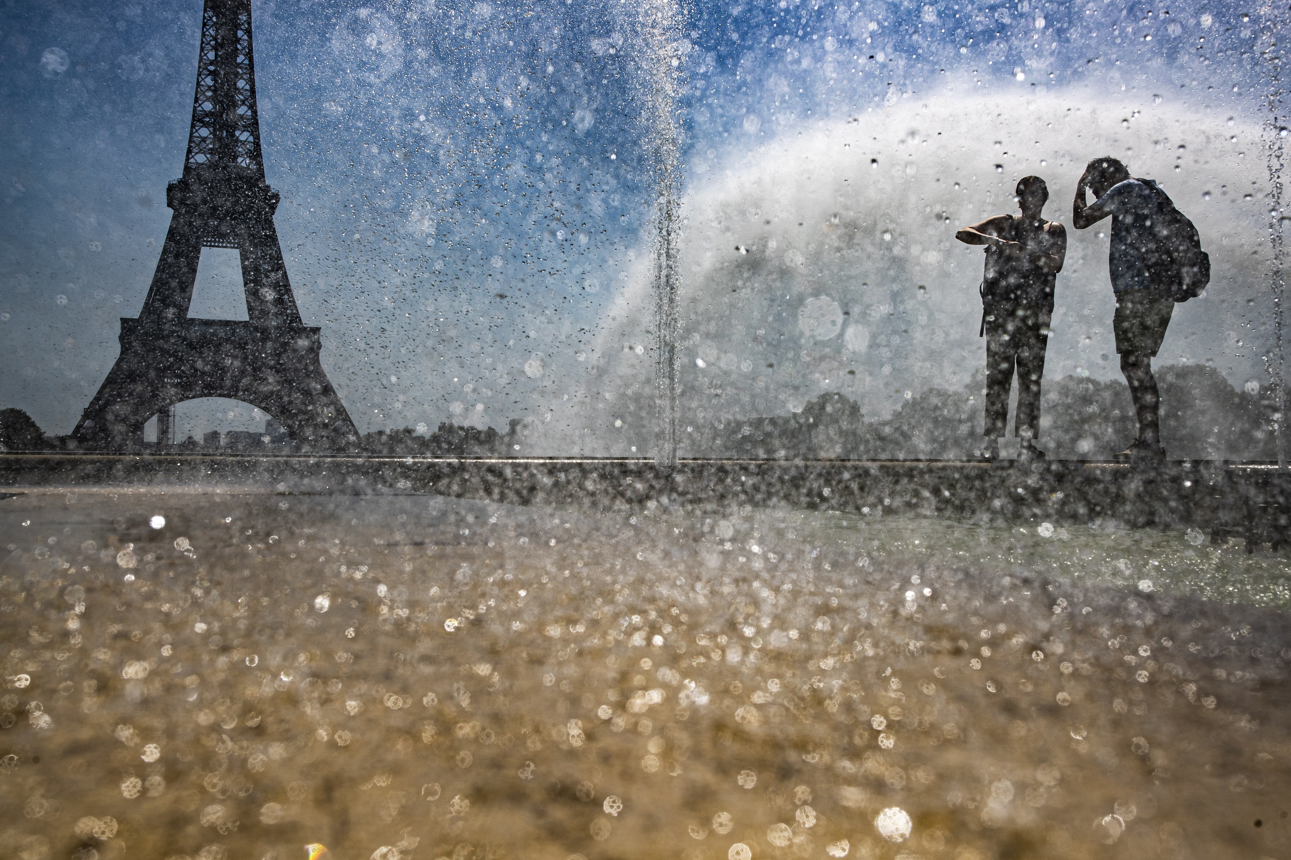 epa07735299 People cool down at the fountains of Trocadero, across from the Eiffel Tower, during a heatwave in Paris, France, 23 July 2019.  According to forecast, France will experience high temperatures across the country.  EPA/IAN LANGSDON