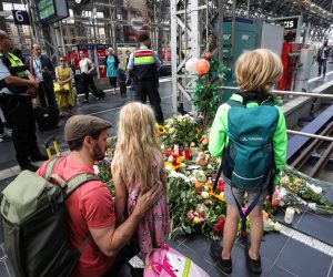 epa07748273 A father with his kids put flowers and candles to pay tribute at the main train station in Frankfurt am Main, Germany, 30 July 2019, one day after an eight-year-old boy died after being pushed onto the rail tracks in front of an oncoming train. The boy's mother was also pushed onto the tracks but was able to save herself. One man has been arrested in connection with the attack.  EPA/ARMANDO BABANI