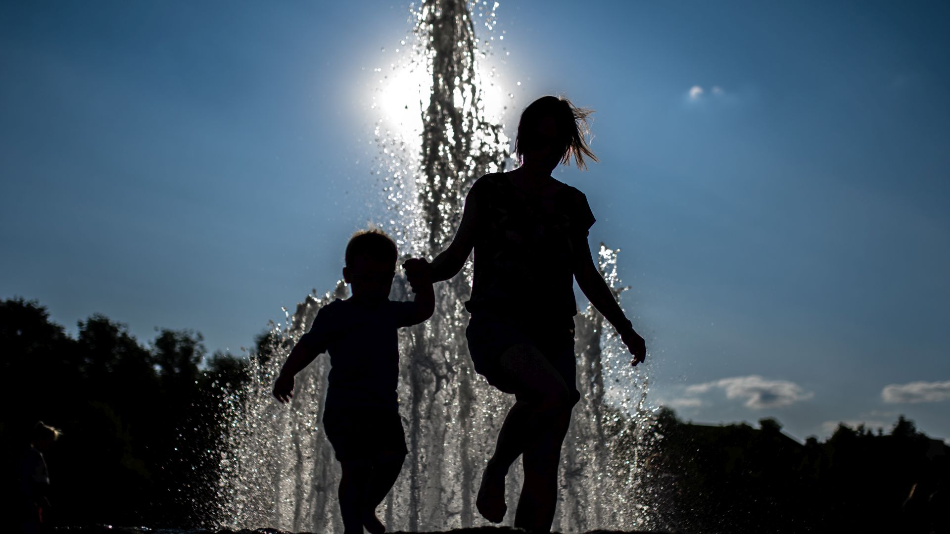 epa07742763 A woman and a child walk hand in hand in front of a fountain at Lustgarten park, during a hot and sunny weather in Berlin, Germany, 26 July 2019. Germany experiences a heatwave with temperatures up to 41 degrees Celsius.  EPA/CLEMENS BILAN
