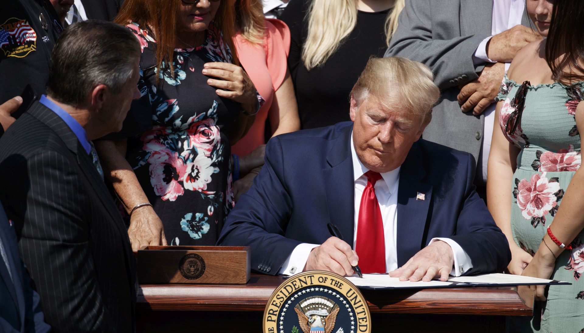 epa07747590 US President Donald J. Trump, with 9/11 first responders and family members, signs in a signing ceremony for H.R. 1327, an act to permanently authorize the September 11th victim compensation fund in the Rose Garden of the White House in Washington, DC, USA, 29 July 2019. The fund provides billion of dollars in health care compensation for police officers, firefighters and other first responders to the terrorist attacks of Sept. 11, 2001.  EPA/SHAWN THEW