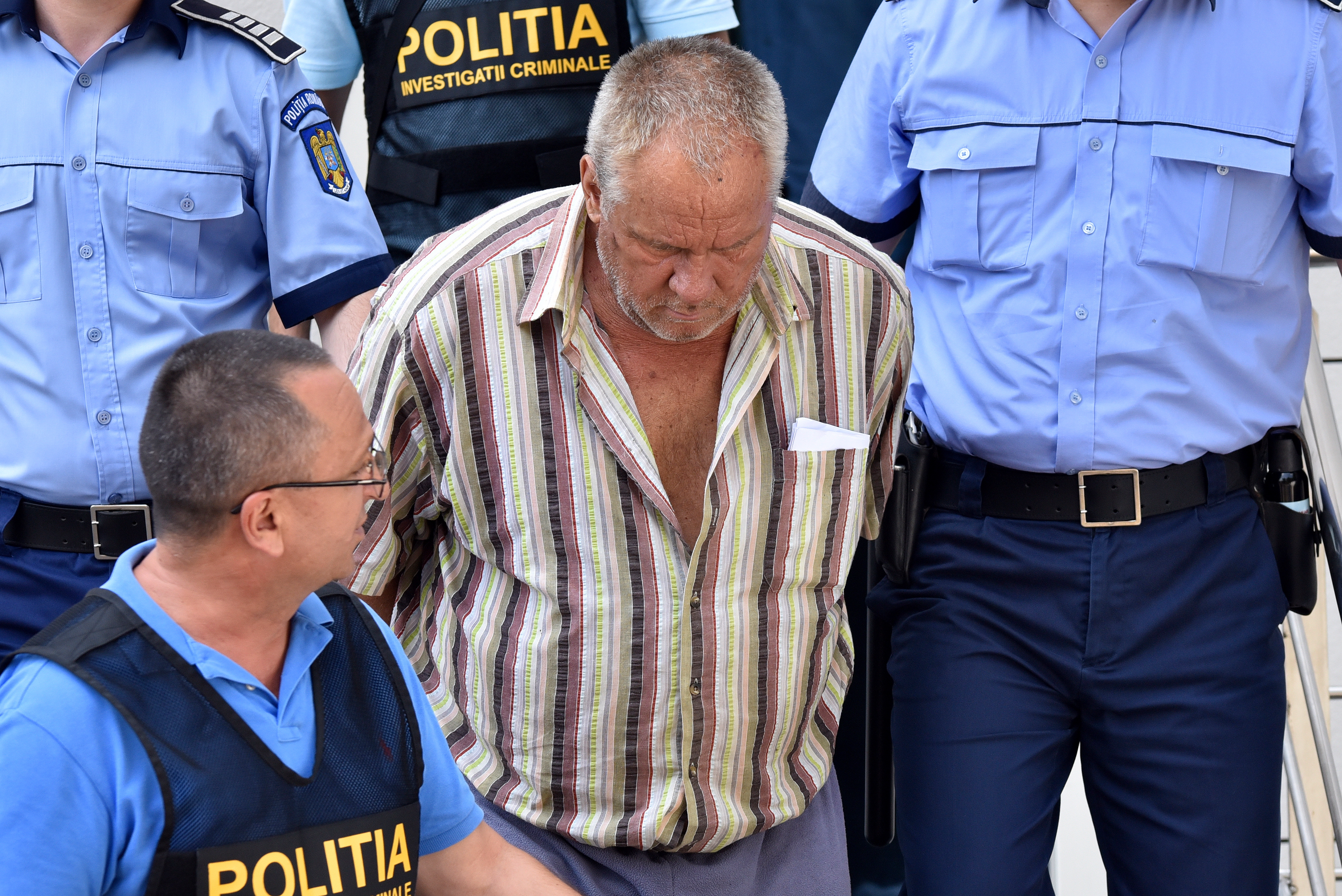 epa07754729 (FILE) - Romanian police officers escort the alleged suspect (C) at Dolj county court, Romania, 27 July 2018, reissued 03 August 2019, after the man was accused of kidnapping a 15 year old girl, who is now confirmed by forensics to have been killed, in the southern city of Caracal, Romania. Alexandra a 15-year-old girl, disappeared on 25 July 2019 hitchhiking to Caracal. Media reports on 28 July 2019 that despite making three emergency calls telling police where she was being held and she had been abducted by a car driver Alexandra's calls went unheeded. Romanian police did not search the property until 19 hours after the girl's last call finding human remains and jewellery. Today, the DIICOT (Directorate for the Investigation of Organized Crime and Terrorism)prosecutors make public the fact that forensic biological evidence taken from the suspect's home matched Alexandra's DNA, announcing her relatives last night.  EPA/BOGDAN DANSECU ROMANIA OUT