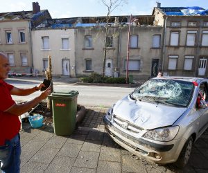 epa07765513 A person using a mobile phone stands in front of a damaged car after a tornado hit the town of Petange, Luxembourg, 10 August 2019. According to reports, a rare tornado caused considerable damage in Petange and Bascharage on 09 August evening in the south of Luxembourg, injuring at least 14 people.  EPA/JULIEN WARNAND