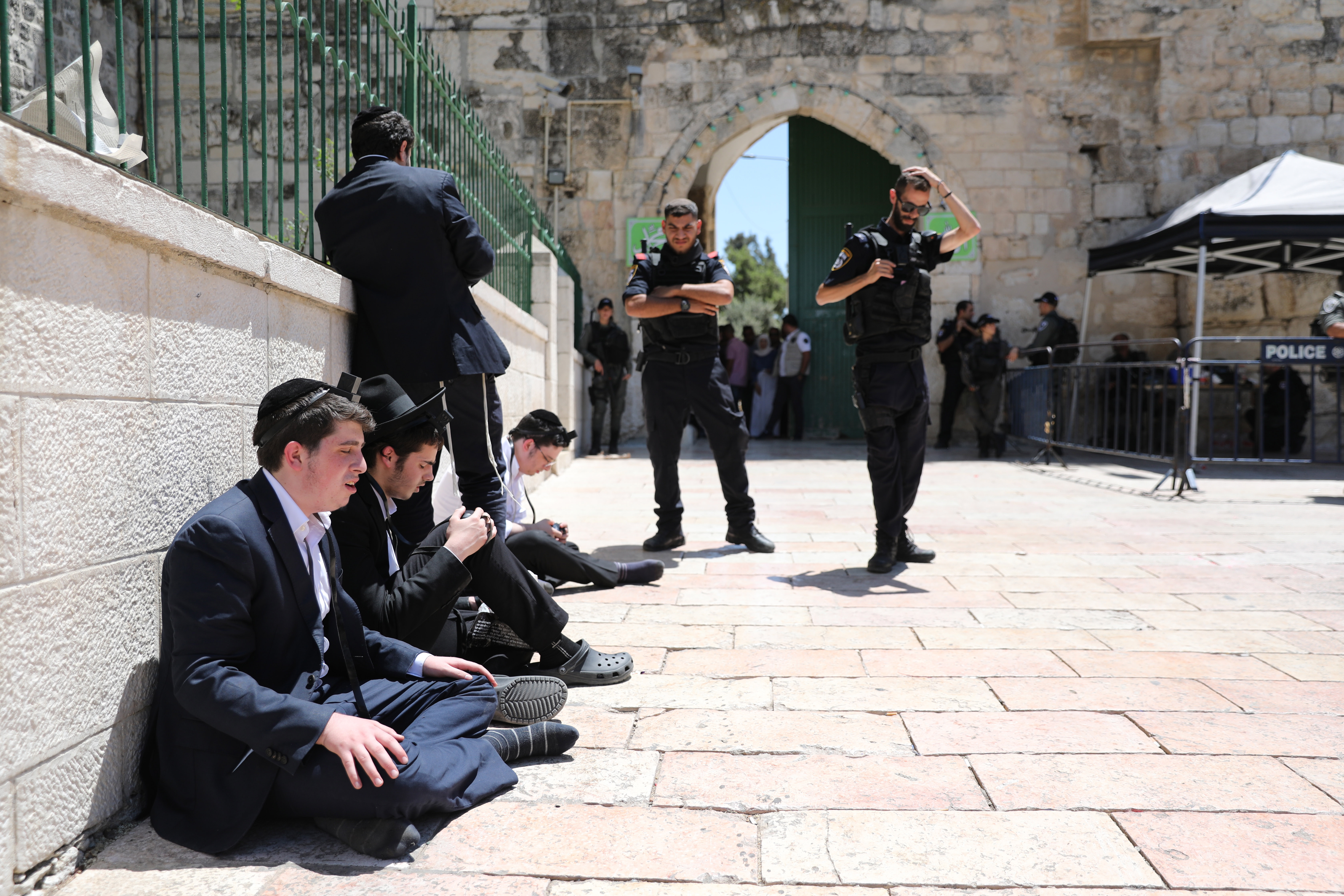 epa07767996 Orthodox Jews perform a prayer near the lion gate at the entrance to the Al Aqsa Mosque compound as they mark Tisha B'av in the old city of Jerusalem, 11 August 2019. Media reports tension increased at Temple Mount after Israeli police allowed entry of Jews during the annual fast day in Judaism Tisha B'Av while thousands of Muslim worshipers were marking the Eid al Adha holiday. Palestinian sources reported 14 people were injured during clashes, while police said four police officers were injured.  EPA/ABIR SULTAN