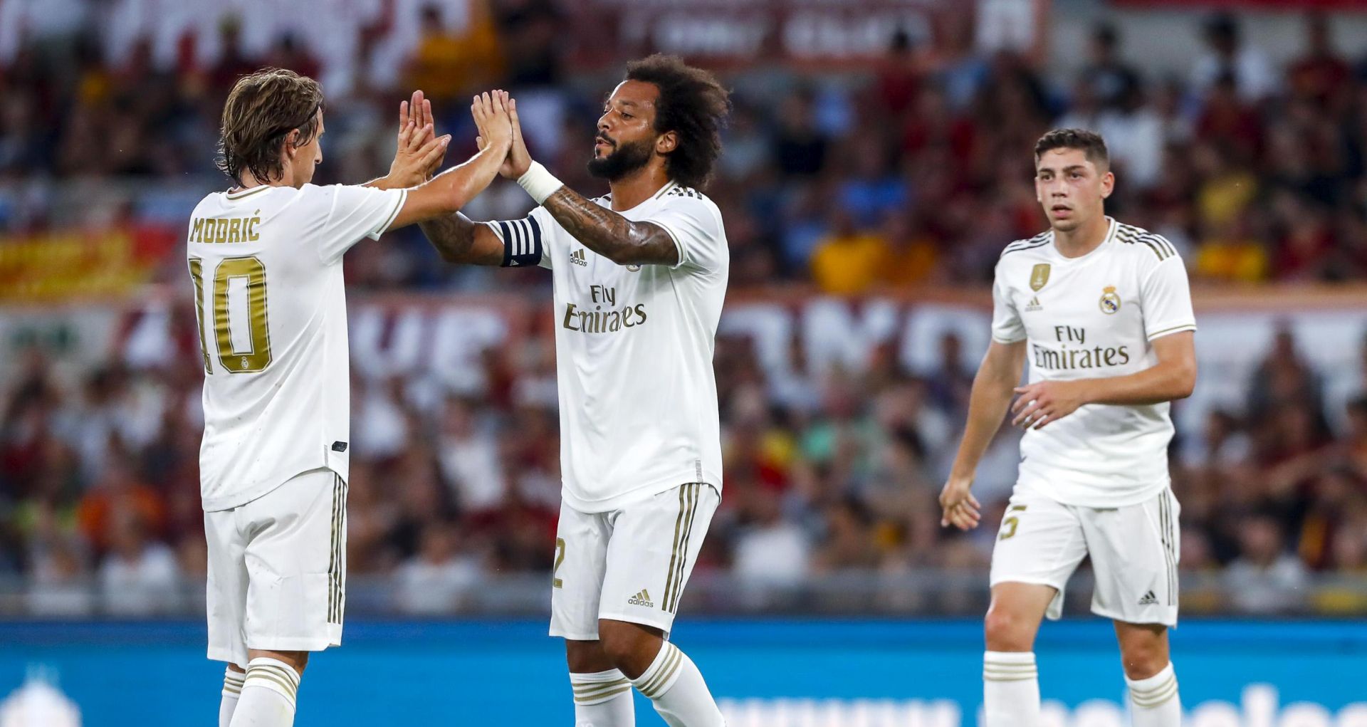 epa07768781 Real Madrid's Marcelo (C) jubilates with his teammate Luka Modric (L) after scoring the 0-1 goal during the international friendly soccer match AS Roma vs Real Madrid CF at Olimpico stadium in Rome, Italy, 11 August 2019.  EPA/ANGELO CARCONI