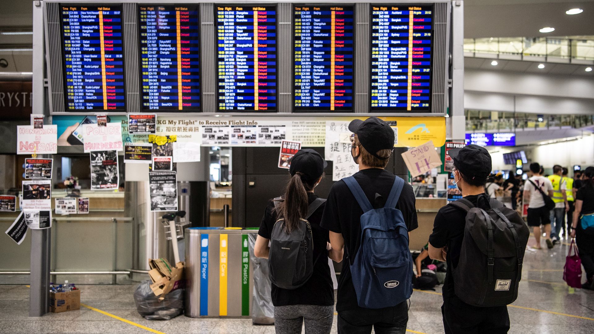 epa07770186 Protesters stand in front of a flight display board showing cancelled flights as they occupy Hong Kong Chek Lap Kok International Airport in Hong Kong, China, 12 August 2019. According to media reports, the Airport Authority said it is virtually shutting down the airport, one of the busiest in the world, as thousands of protesters occupied both the arrival and departure halls of Chek Lap Kok. Hong Kong has been gripped for weeks by mass protests, which began in June 2019 over a now-suspended extradition bill to China and have developed into an anti-government movement.  EPA/LAUREL CHOR