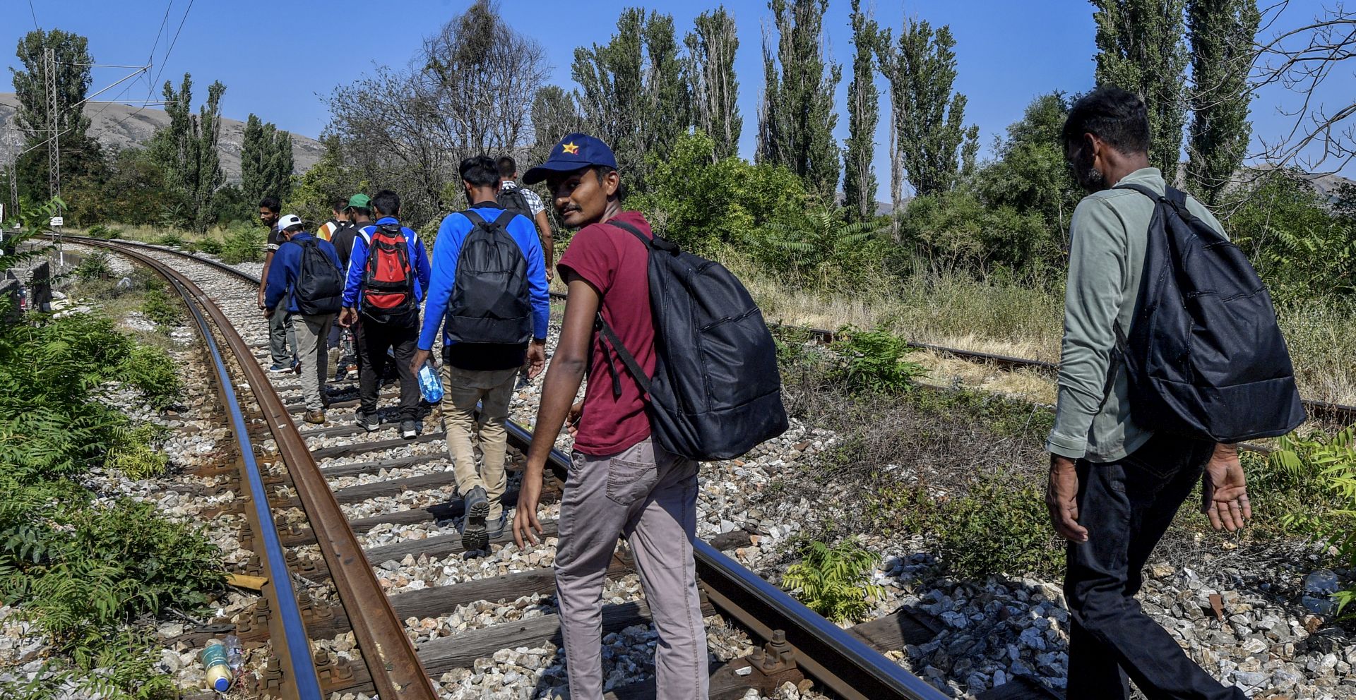epa07772811 A group of Pakistani illegal migrants walk on the railroad by the town of Veles, Republic of North Macedonia on 14 August 2019. Reports state that they have been traveling from the Greek - North Macedonian border to the town of Veles  (around 100 km) for seven days. Although the Balkan migrant route has been officially closed since 03 March 2016, small groups of migrants are still illegally passing the border between Greece and North Macedonia and travel through North Macedonia on their way to western Europe. Some travel this road by foot, while others use the transport offered by migrant smugglers. Beside the North Macedonian police and army, the border with Greece is being patrolled by police forces from other European countries.  EPA/GEORGI LICOVSKI