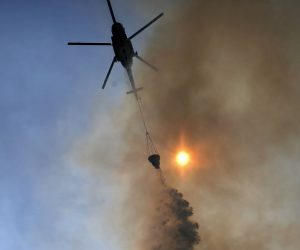 epa07773133 A firefighting helicopter drops water over a forest fire near the village of Makrimalli on the island of Evia, Greece, 14 August 2019. The firefighting forces struggled throughout the night to save the four villages that were threatened by the major wildfire on Evia. The fire has burnt a huge part of a pine forest. The prime minister said that the government will make interventions in the overall operation of the Civil Protection agency after the end of the fire risk season in Greece.  EPA/KOSTAS TSIRONIS