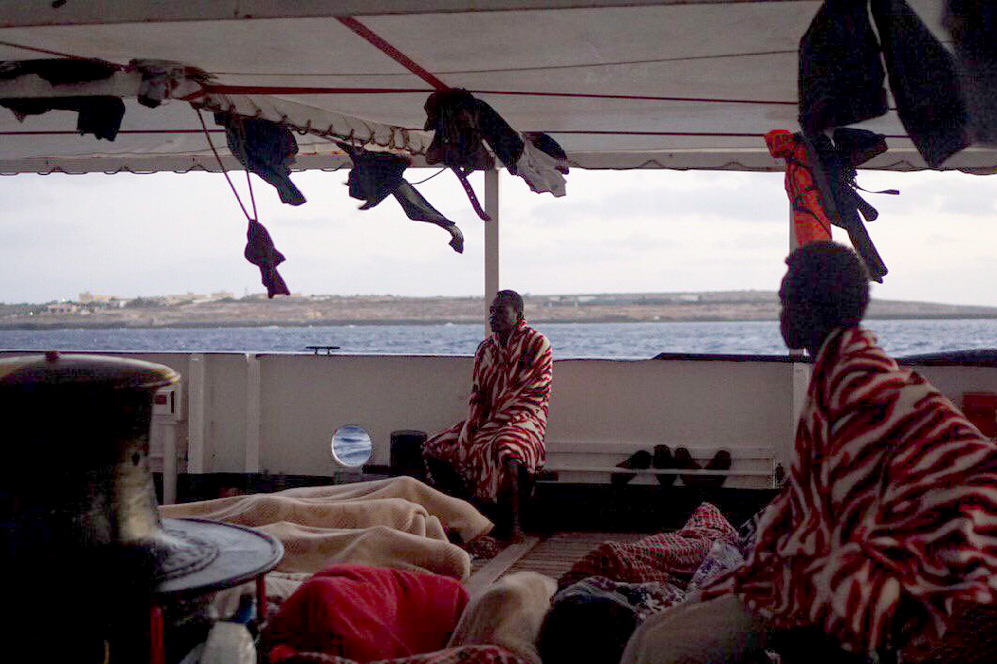 epa07774342 An undated handout photo made available by Spanish NGO Proactiva Open Arms shows several migrant resting in the deck of the Spanish NGO Open Arms' ship at sea in the Mediterranean (issued 15 August 2019). The 147 migrants, on board the ship, reached Italian waters off Lampedusa island a day after the Lazio Regional Administrative Court accepted its appeal, suspending the ban on entry into Italian waters ordered by Italian Interior Minister Matteo Salvini. The ship has been waiting to get into a port since last 01 August.  EPA/FRANCISCO GENTICO/OPEN ARMS HANDOUT -- BEST QUALITY AVAILABLE -- HANDOUT EDITORIAL USE ONLY/NO SALES