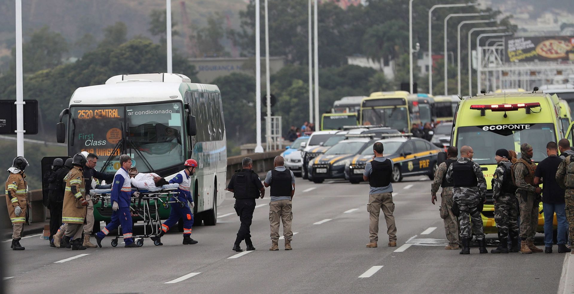 epa07782076 A woman is taken on a stretcher after she passed out moments after she was released from a bus by a hijacker in the Rio-Niteroi bridge in Rio de Janeiro, Brazil, 20 August 2019. A masked armed man hijacked a bus and keeps passengers and driver as hostages while he threatens to burn the vehicle with petrol.  EPA/ANTONIO LACERDA