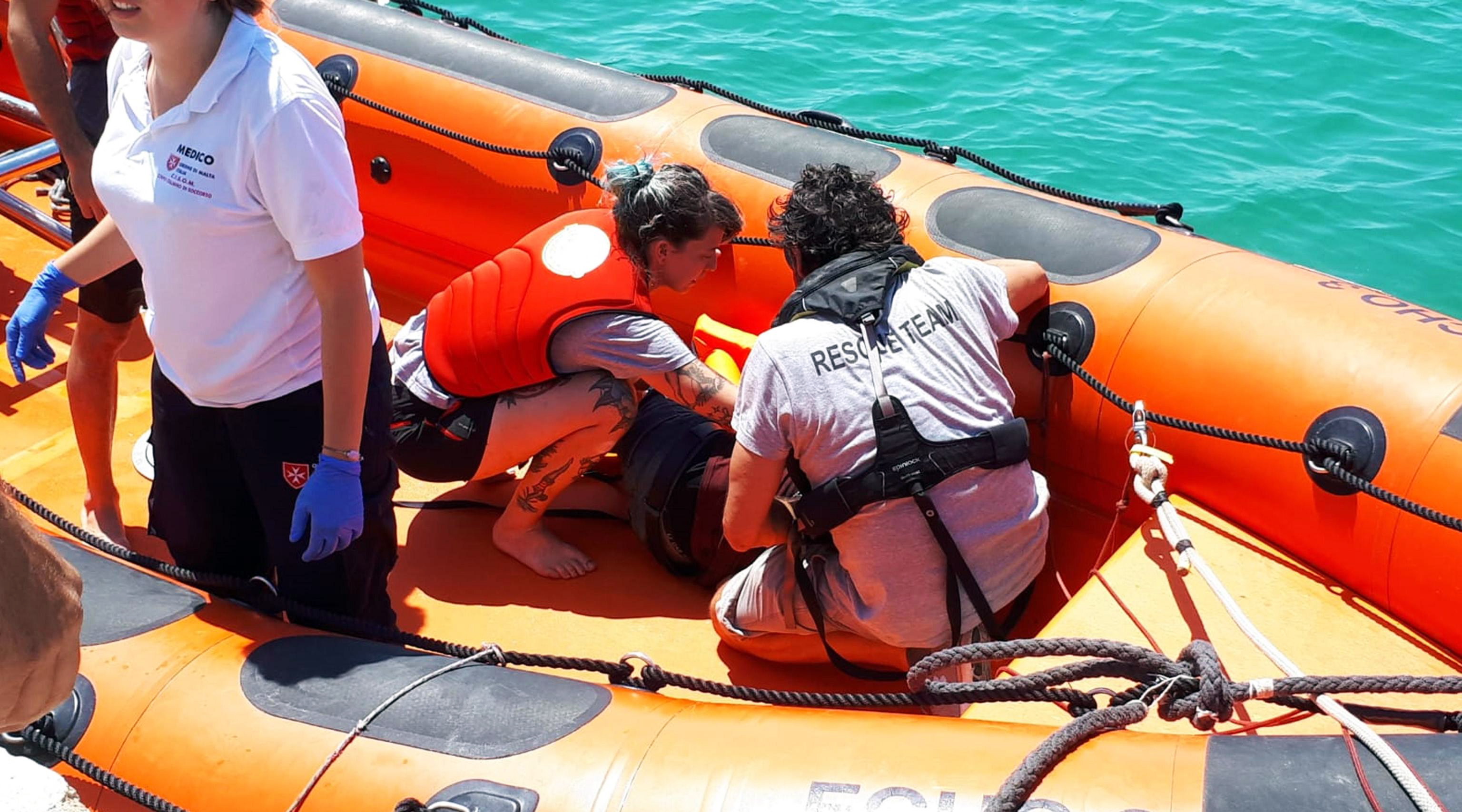 epa07782069 Rescuers give first-aid to some of the migrants, who reportedly dived into the sea from the Spanish NGO rescue ship Open Arms in an attempt to swim to the coast, in Lampedusa, southern Italy, 20 August 2019. Some migrants reportedly dived into the sea from the Spanish NGO rescue vessel Open Arms in an attempt to swim and reach the coast. The rescue boat is anchored about 800 meters off the rocks of Lampedusa Island. The men were recovered by an Italian Coast Guard patrol boat.  EPA/ALFREDO PECORARO