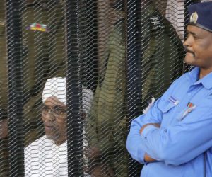 epa07789690 Sudan's ousted President Omar Hassan al-Bashir (L) looks out from inside the accused  cage, during his trial in Khartoum, Sudan, 24 Auguste 2019. Al-Bashir stepped down in April 2019 after the months long uprising which led to hundreds of deaths.  EPA/AMEL PAIN