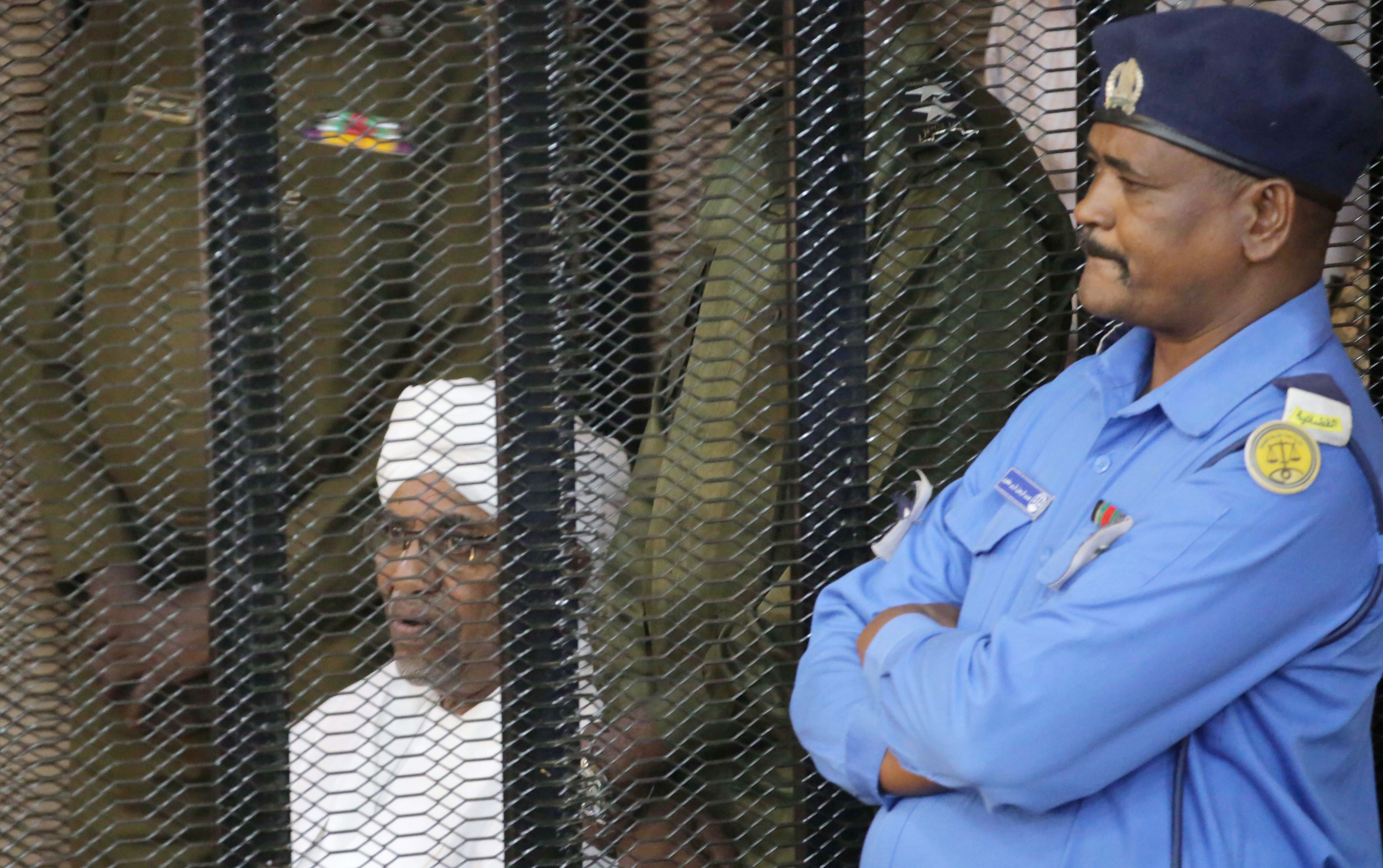 epa07789690 Sudan's ousted President Omar Hassan al-Bashir (L) looks out from inside the accused  cage, during his trial in Khartoum, Sudan, 24 Auguste 2019. Al-Bashir stepped down in April 2019 after the months long uprising which led to hundreds of deaths.  EPA/AMEL PAIN