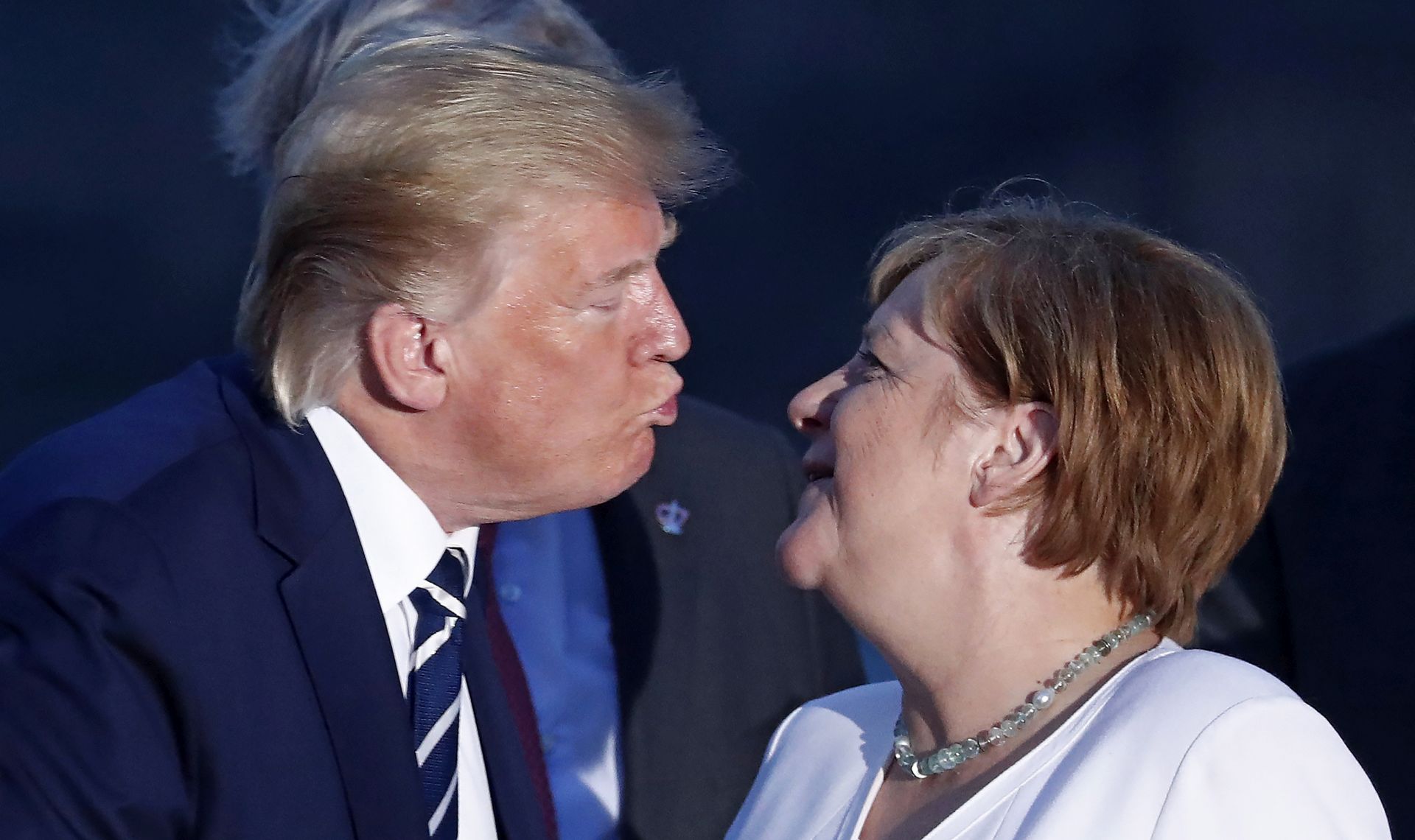 epa07793896 US President Donald J. Trump (L) kisses German Chancellor Angela Merkel (R) as they pose for the family photo during the G7 summit at Casino in Biarritz, France, 25 August 2019. The G7 Summit runs from 24 to 26 August in Biarritz.  EPA/IAN LANGSDON