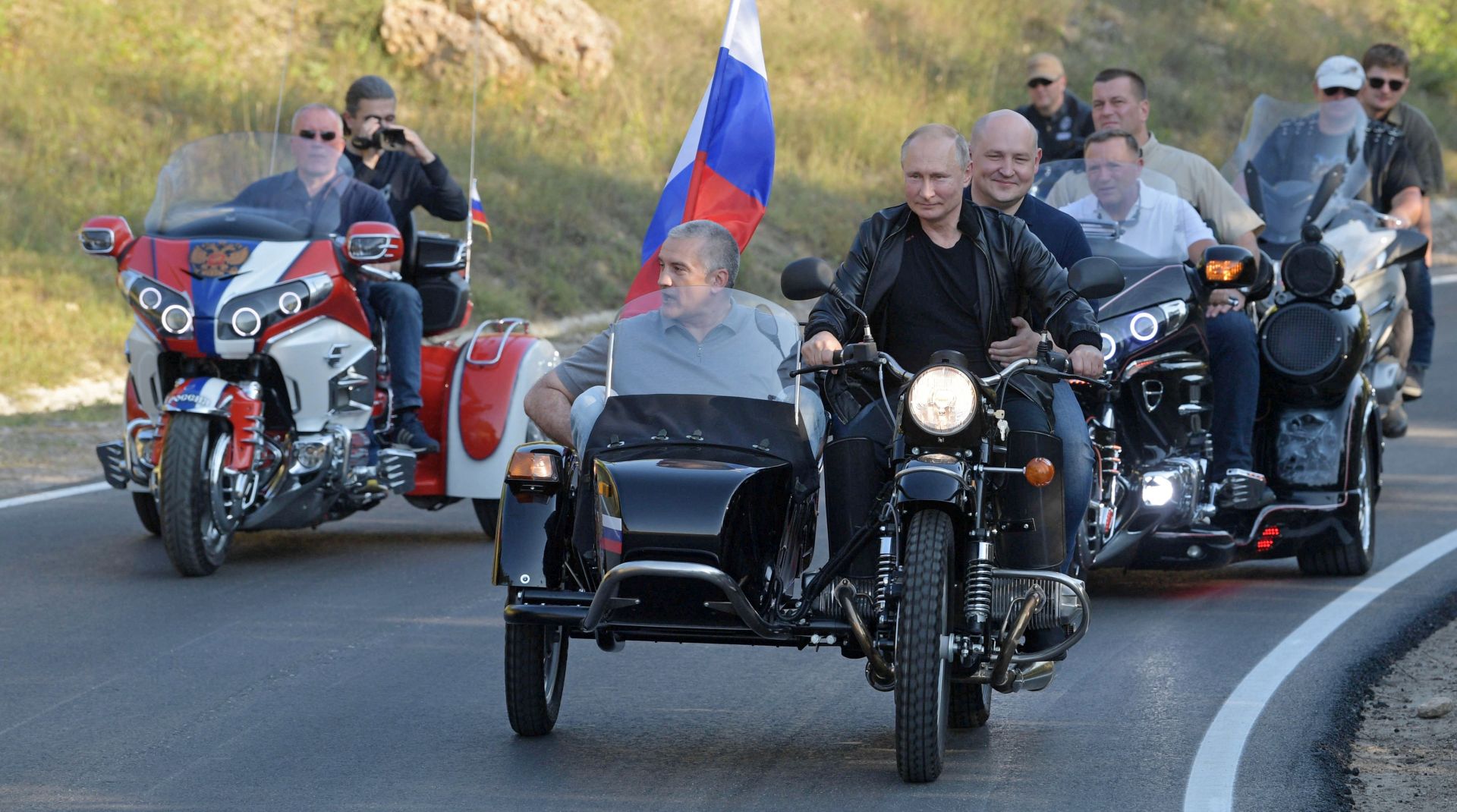 epa07768102 Russian President Vladimir Putin (C) rides an Ural motorbike before the Babylon's Shadow bike show in Sevastopol, Crimea, 10 August 2019. Putin and the Night Wolves bikers took part in an annual show organised by the motorcycle club in the Black Sea peninsula, annexed by Russia from Ukraine in March 2014, while tens of thousands of people on 10 August protested against Putin's government following local election violations.  EPA/ALEXEI DRUZHININ / SPUTNIK / KREMLIN POOL / POOL