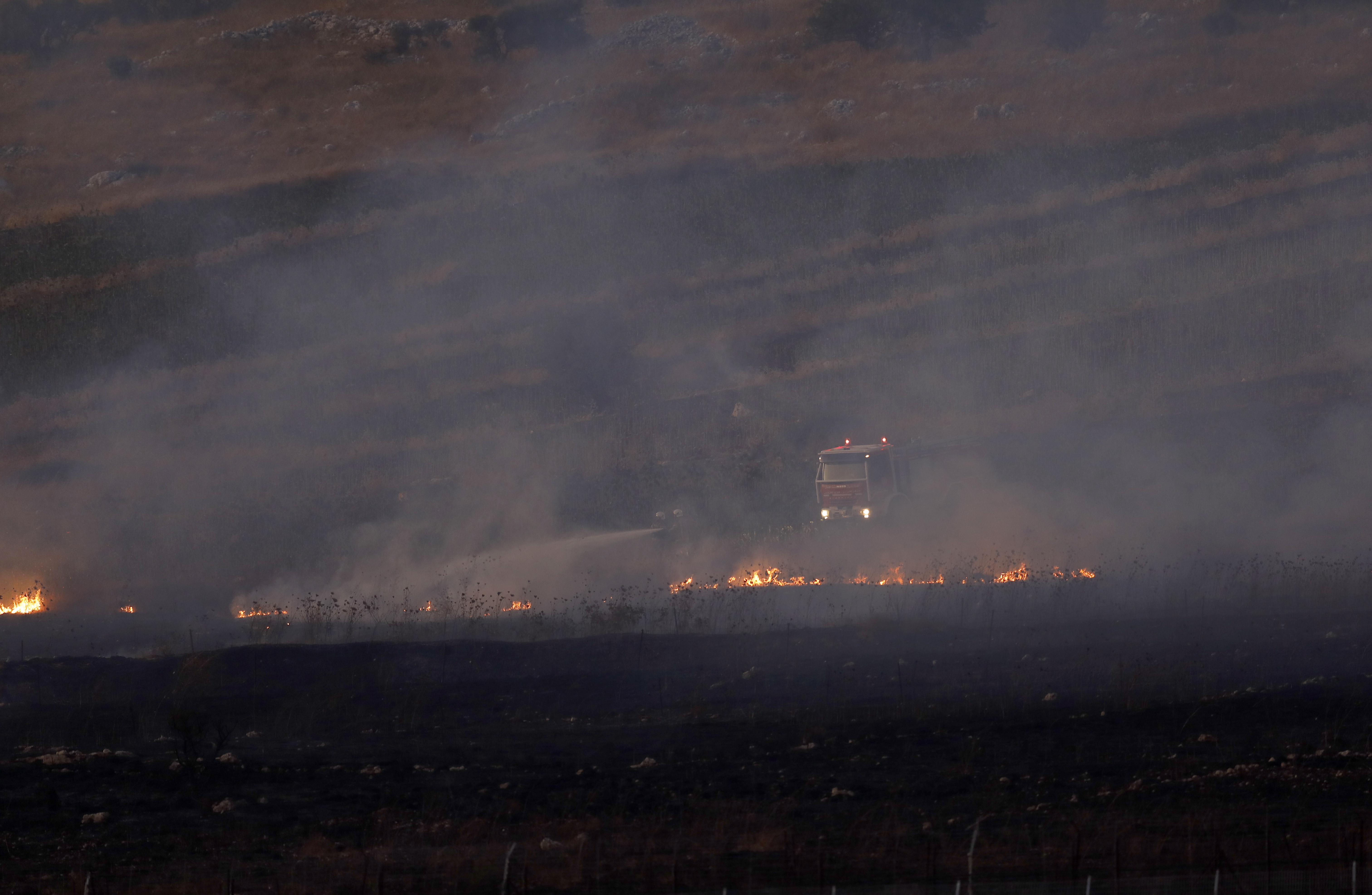 epa07811184 Lebanese firefighters extinguish the fire caused by Israeli shell as seen from the Israeli side of the border near the village of  village of Avivim, 01 September 2019. According to reports, tension between Israel and Lebanese militant group Hezbollah continues to escalate since last week following strikes on targets in Syria and Israeli drones fell over southern suburb of Beirut.  Hezbollah fired  anti-tank missile fire towards an Israeli army  base next to  the village of Avivim on the Israeli-Lebanese  border with no injured , in  responded Israeli army  launching approximately 100 artillery shells at the sources of the fire.  EPA/ATEF SAFADI