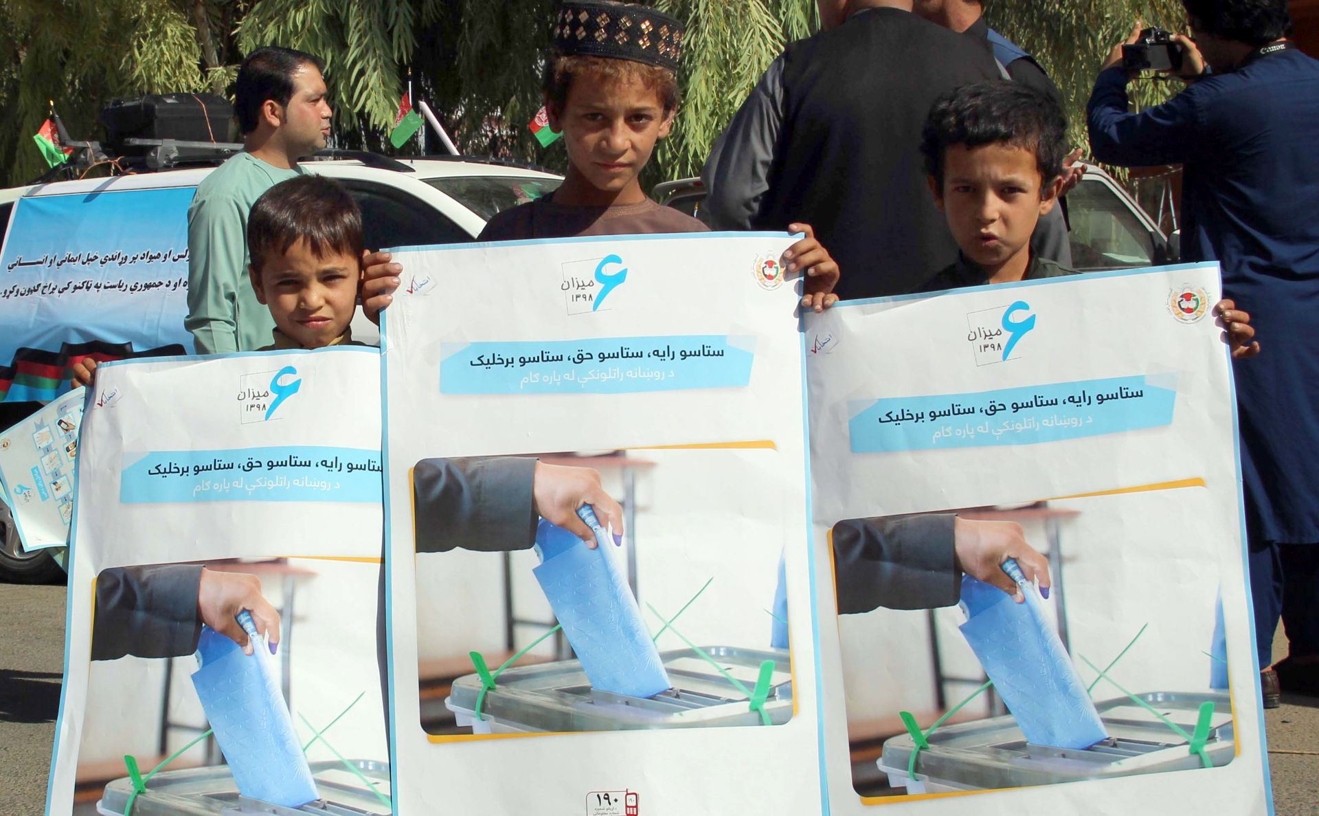 epa07870703 Afghan boys hold posters, featuring the importance of ballot, distributed by the Afghan Independent Election Commission (IEC) on roads ahead of the Presidential elections in Helmand, Afghanistan, 26 September 2019. Presidential elections in Afghanistan are scheduled for 28 September, with a total of 18 candidates, including incumbent President Mohammad Ashraf Ghani, are running for the post.  EPA/WATAN YAR