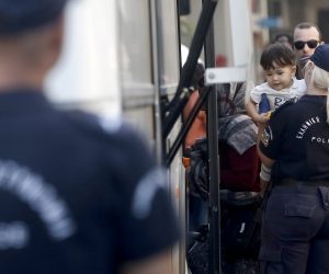 epa07853006 A police officer leads a refugee girl on a bus during a police operation evacuating buildings squatted mostly by migrant families in central Athens, Greece, 19 September 2019. A large police operation to evacuate buildings in downtown Athens squatted mostly by migrant families got underway on 19 September 2019 morning.  EPA/YANNIS KOLESIDIS