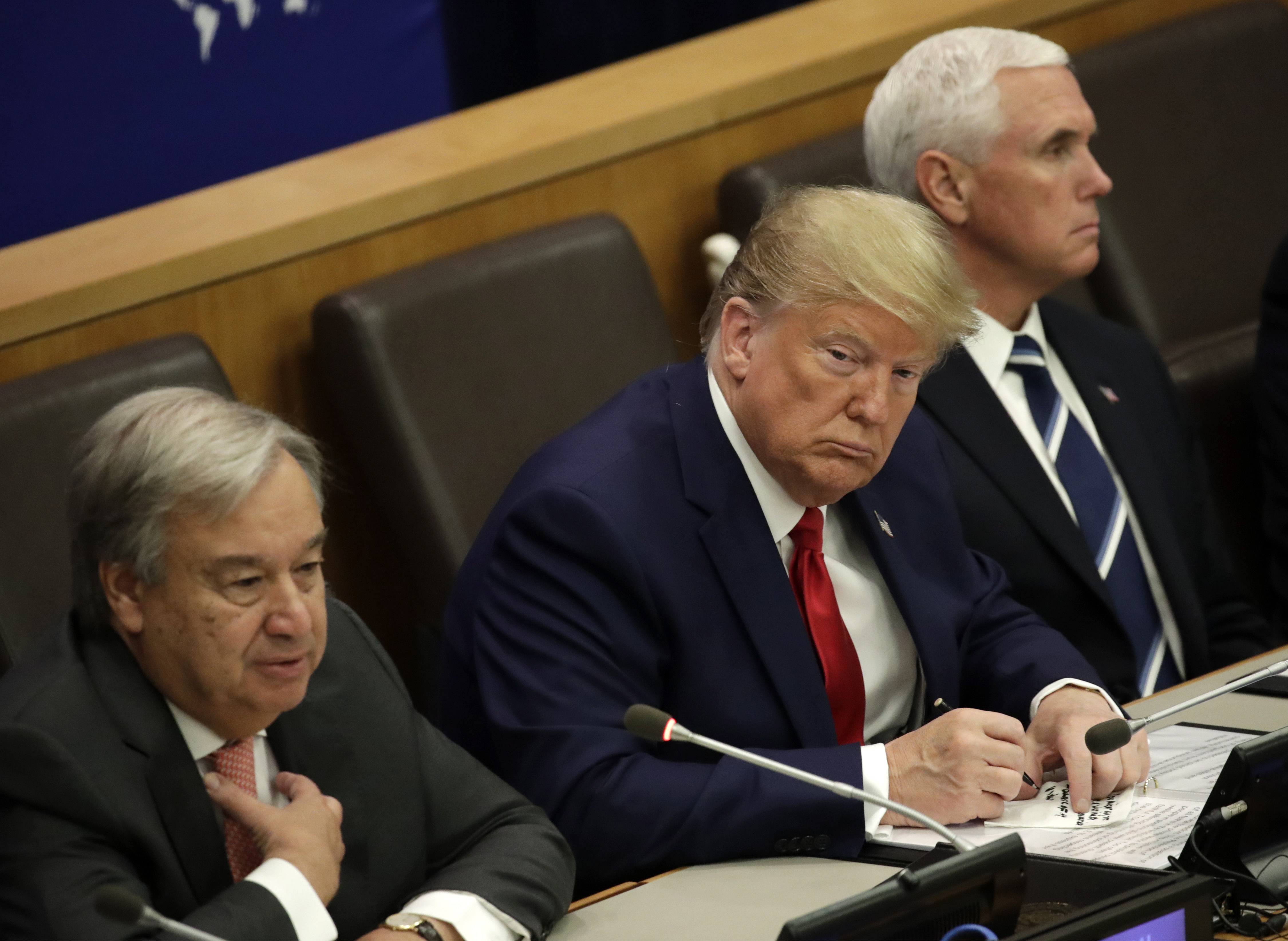 epa07864538 US President Donald J. Trump (C) is seen writing on a piece of paper while listening to United Nations Secretary General Antonio Guterres' (L) remarks at the United Nations for a global call to protect religious freedom with US Vice President Mike Pence (R) ahead of the General Debate of the General Assembly of the United Nations at United Nations Headquarters in New York, New York, USA, 23 September 2019. The General Debate of the 74th session of the UN General Assembly begins on 24 September.  EPA/JASON SZENES