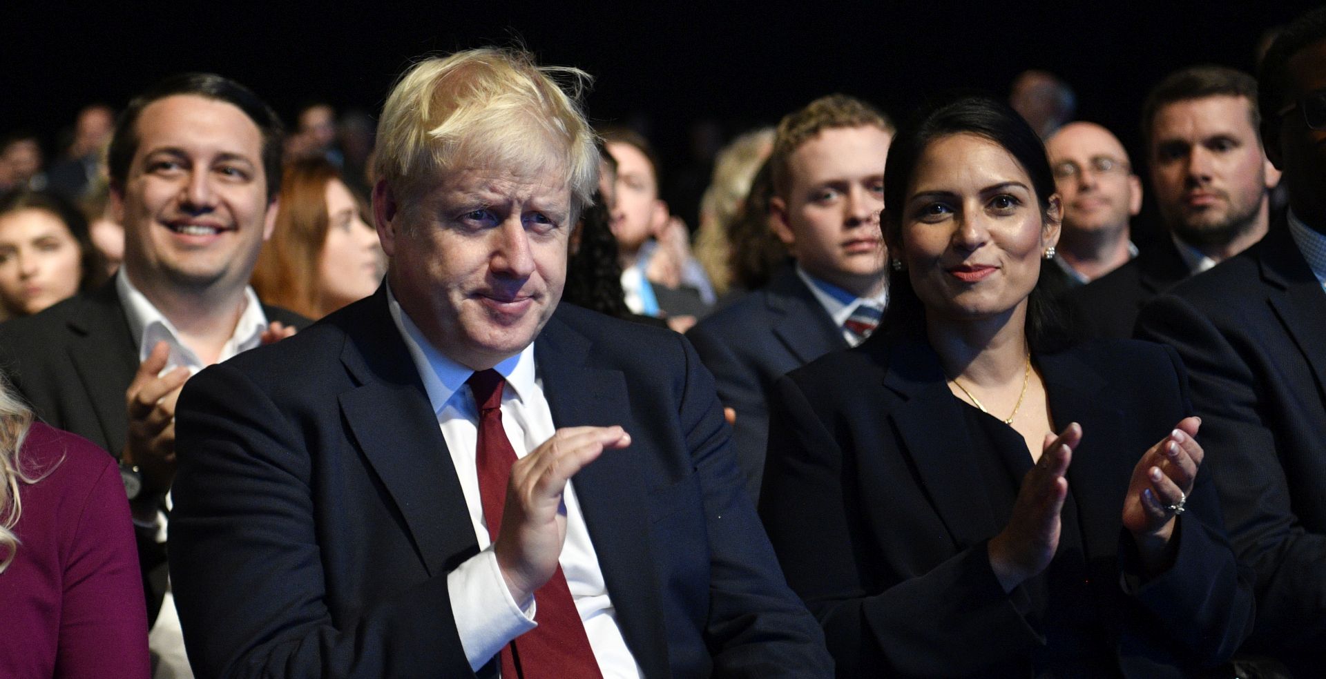 epa07882591 Britain's Prime Minister Boris Johnson (L) and Home Secretary Priti Patel (R) watch as Chancellor of the Exchequer Sajid Javid delivers a speech at the Conservative Party Conference in Manchester, Britain, 30 September 2019. The Conservative Party Conference runs from 29 September to 02 October 2019.  EPA/NEIL HALL