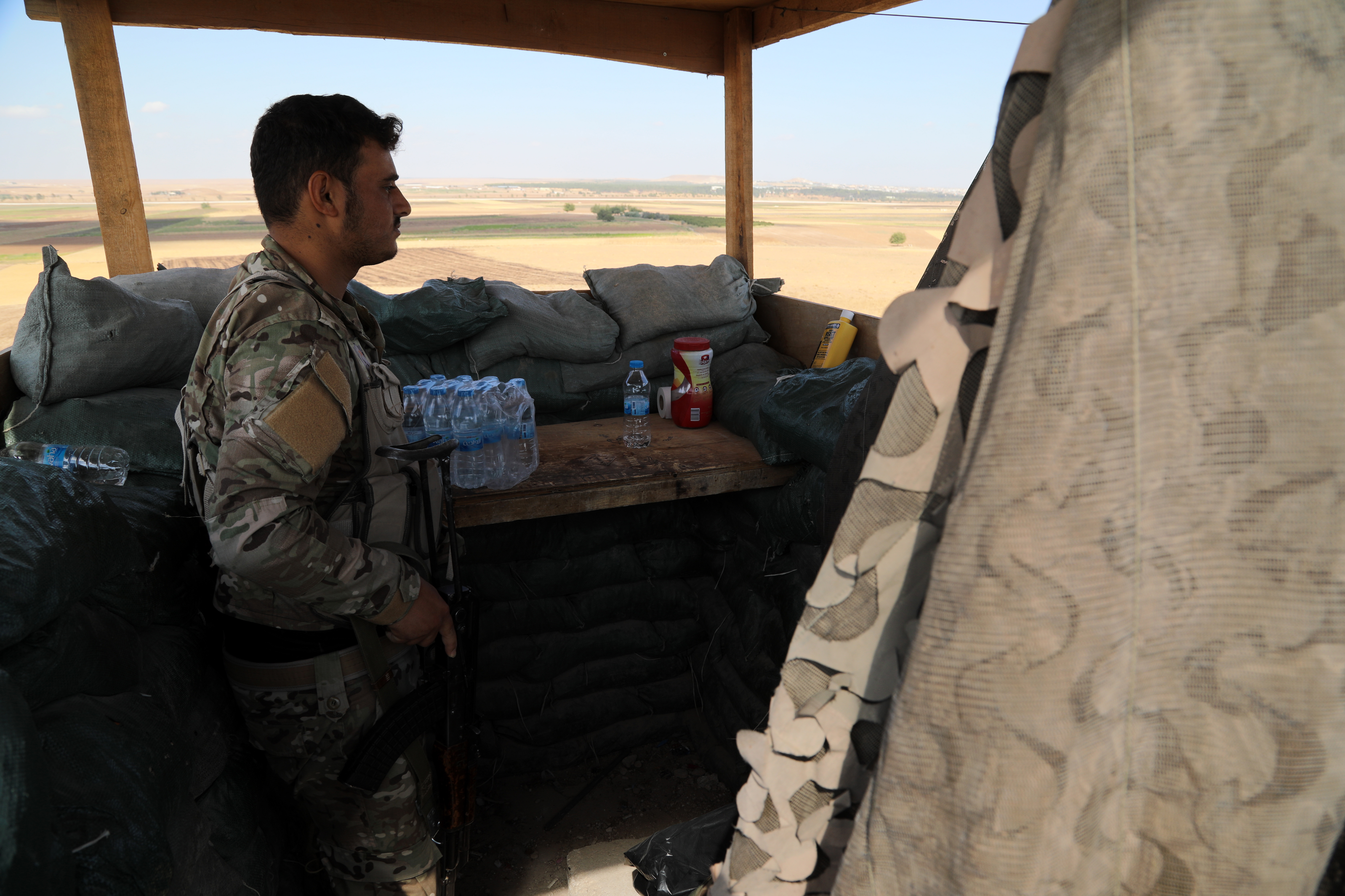 epa07907562 A fighter of the Self-Defense Forces (SDF) keeps watch towards the Turkish border after fighters moved to front lines near the border with Turkey, at Tal Arqam village, Ras al-Ein, north Syria, 07 October 2019 (issued 09 October 2019). US President Donald J. Trump announced the withdrawal of US troops from the area ahead of the anticipated action by Turkish President Recep Tayyip Erdogan.  EPA/STRINGER