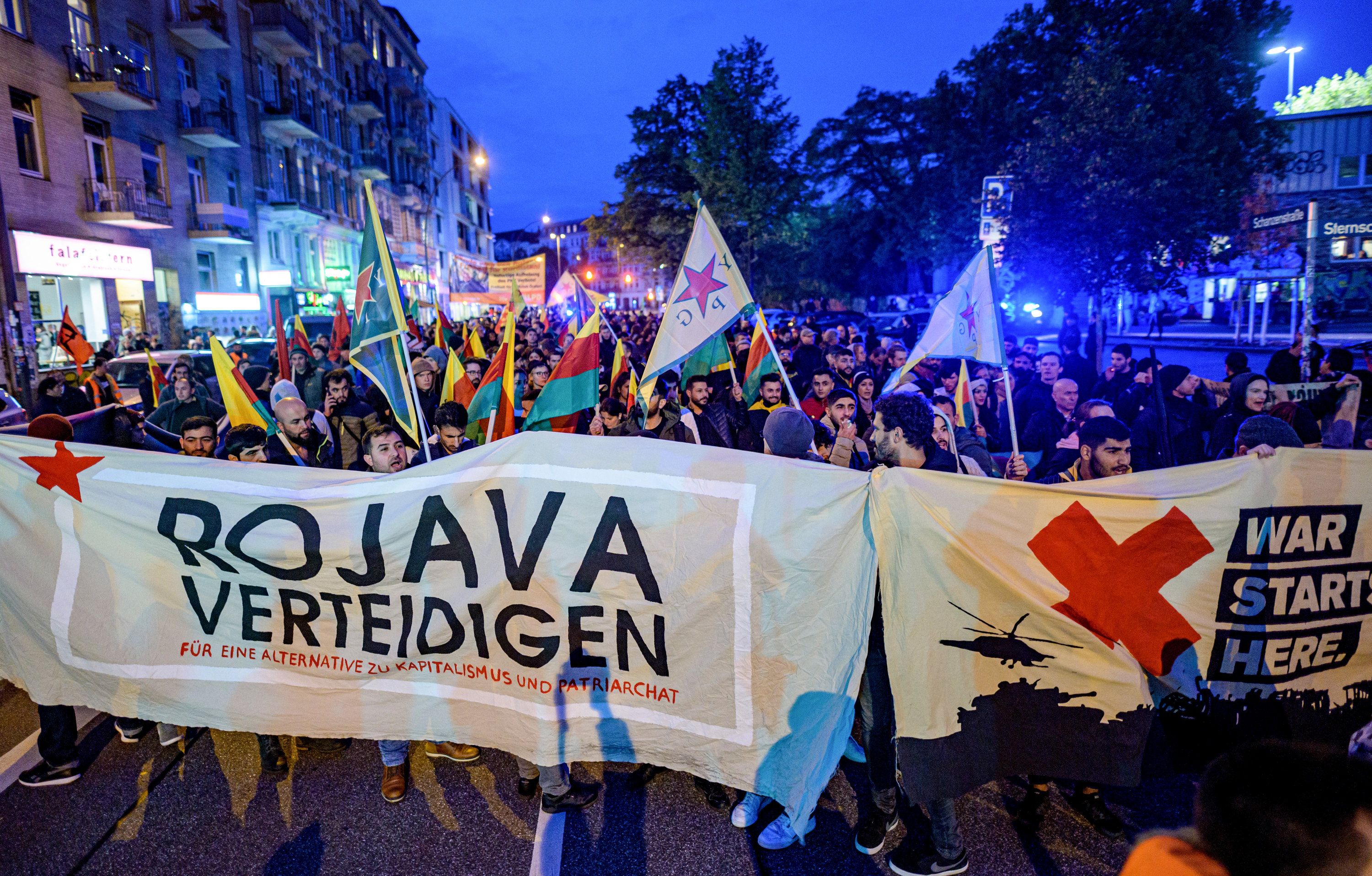 09 October 2019, Hamburg: Kurds hold a banner with the inscription "Defend Rojava" during a protest against the Turkish military offensive in Northern Syria, at Sternschanze station. Photo: Axel Heimken/dpa