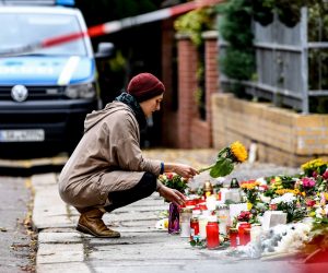 epa07912746 A woman places a flower in front of the synagogue in Halle Saale, Germany, 11 October 2019. According to the police two people were killed on 09 October in shootings in front of the synagogue and a Kebab shop in Halle. A man went on rampage shooting on 09 October and tried to enter the Halle synagogue during the celebrations on the Jewish holiday of Yom Kippur.  EPA/FILIP SINGER