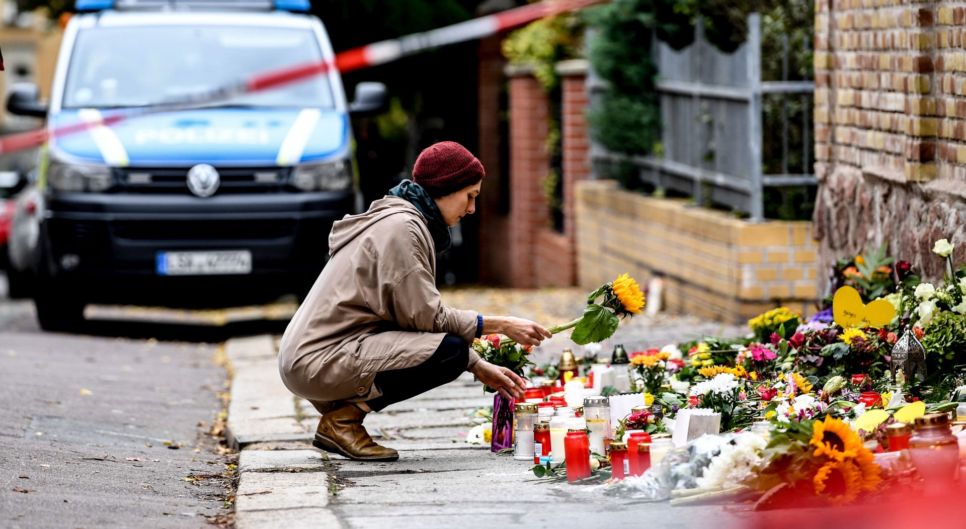 epa07912746 A woman places a flower in front of the synagogue in Halle Saale, Germany, 11 October 2019. According to the police two people were killed on 09 October in shootings in front of the synagogue and a Kebab shop in Halle. A man went on rampage shooting on 09 October and tried to enter the Halle synagogue during the celebrations on the Jewish holiday of Yom Kippur.  EPA/FILIP SINGER