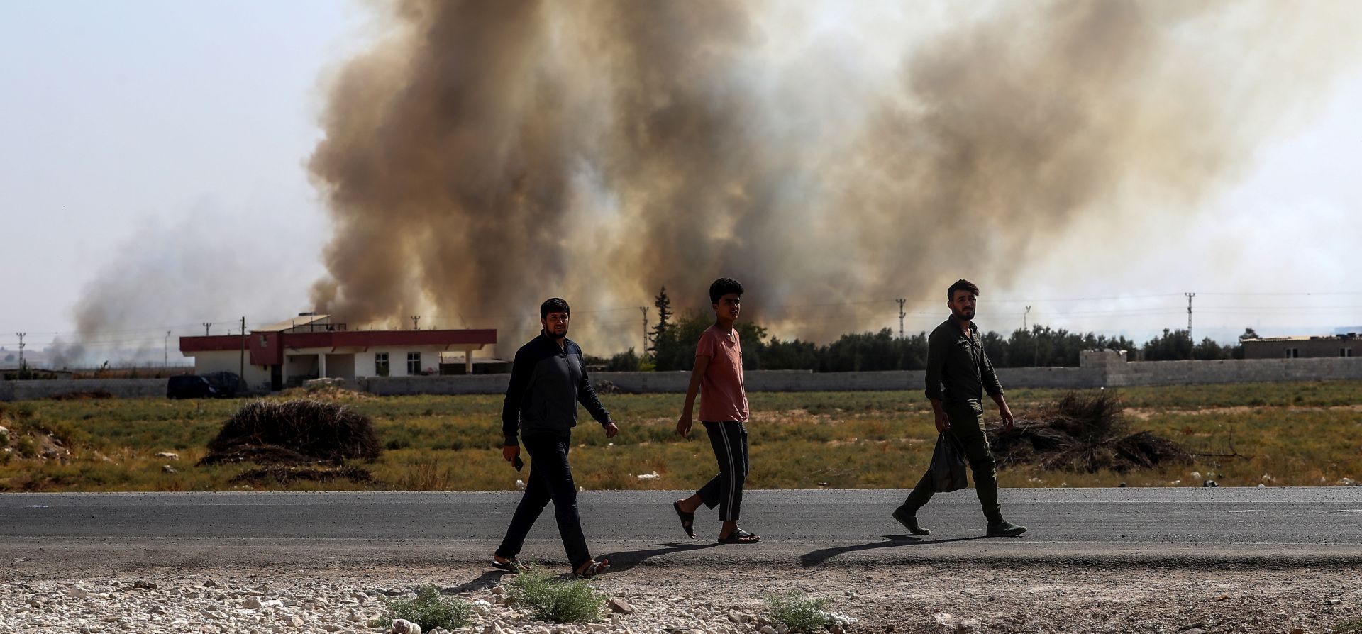 epa07917132 People walk near Turkish-Syria border as smoke rises from targets inside Syria during bombardment by Turkish forces at Tal Abyad town as seen from in Akcakale district in Sanliurfa, Turkey, 13 October 2019. Turkey has launched an offensive targeting Kurdish forces in north-eastern Syria, days after the US withdrew troops from the area.  EPA/SEDAT SUNA