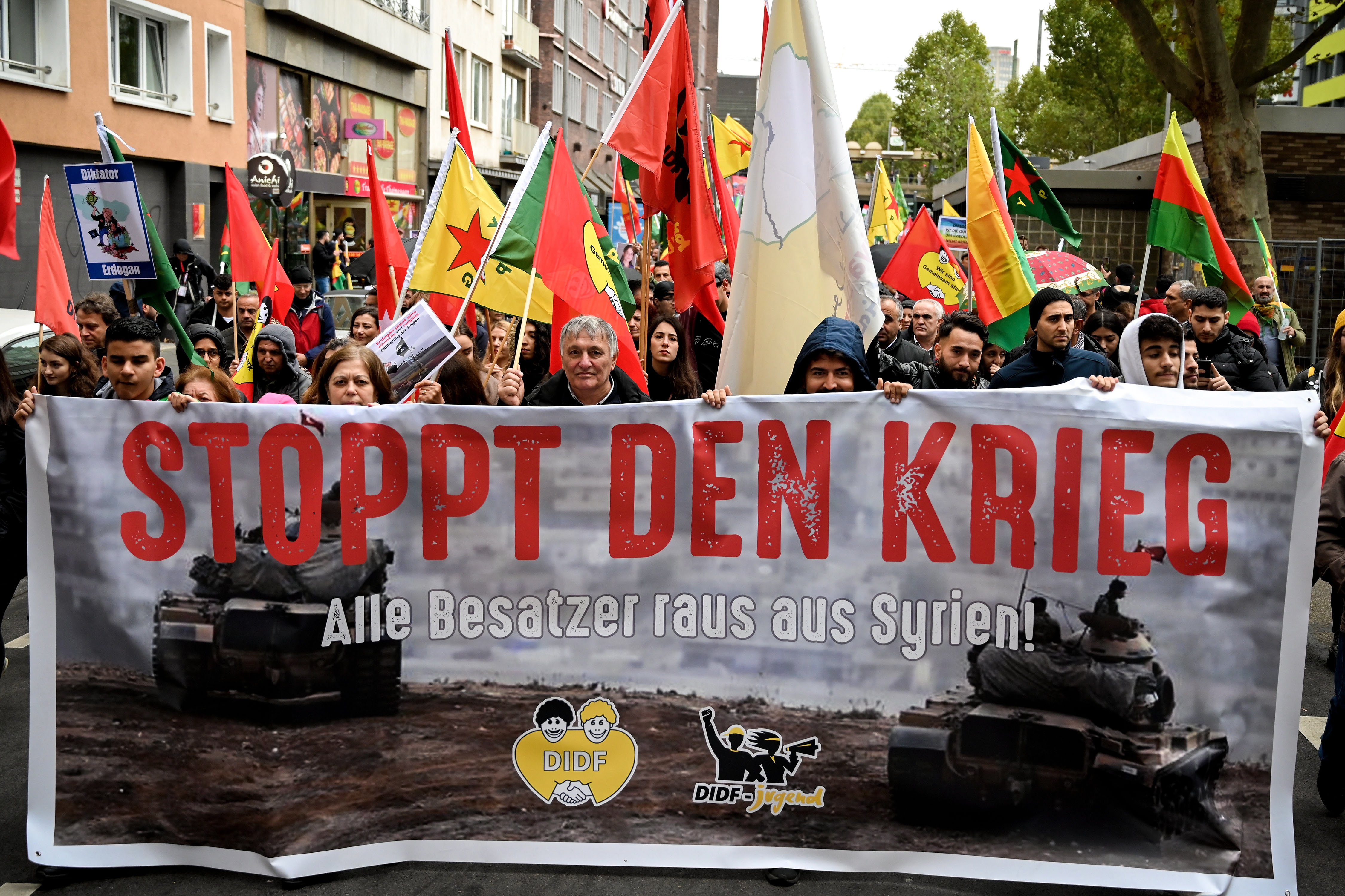 epa07933241 Kurdish activists wave flags and show banners as they protest against the ongoing Turkish military operation in the Syrian border region and the Kurdish territories, in Cologne, Germany, 19 October 2019. The protesters demanded economic sanctions and an arms embargo against Ankara as well as a termination of the EU-Turkey refugee agreement.  EPA/SASCHA STEINBACH