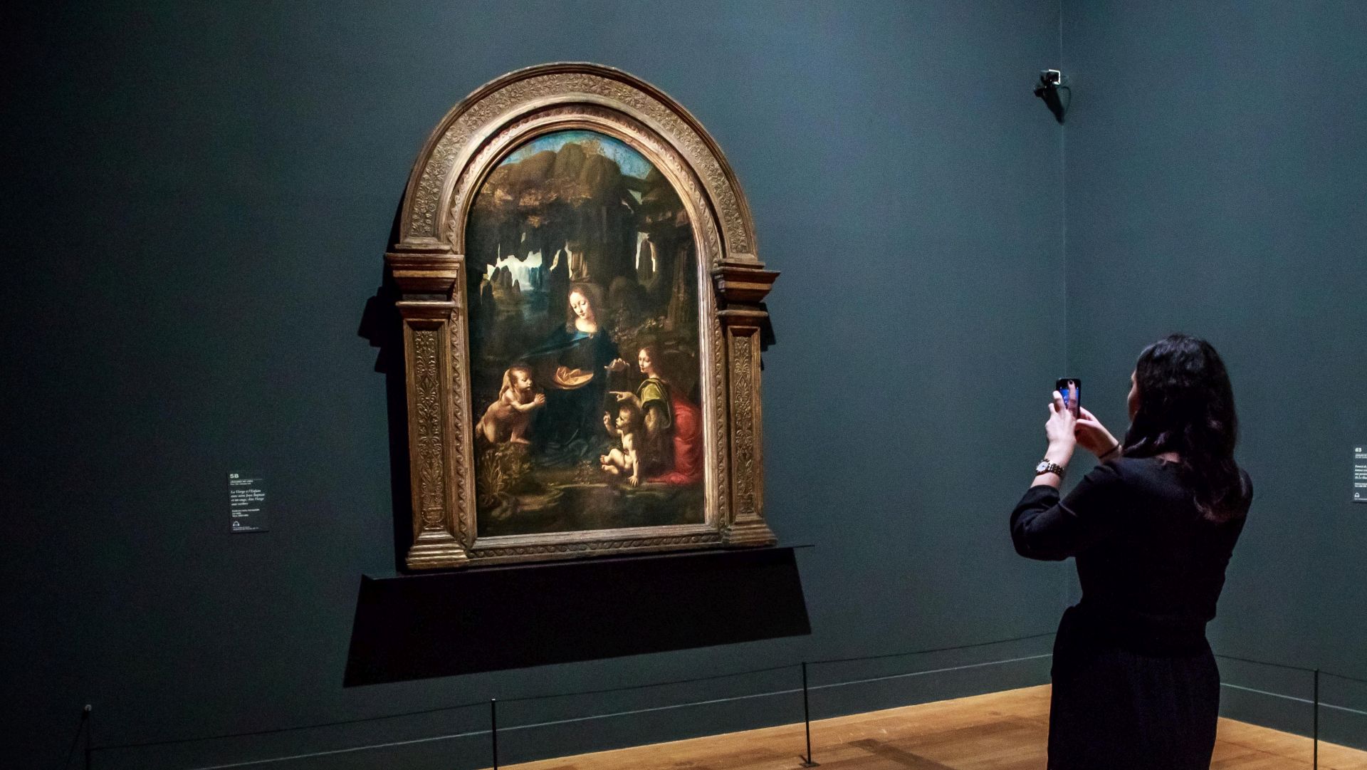 epa07940139 A visitor takes a picture of the painting  entitled 'The Virgin with a Child and Saint John the Baptist' by Italian Renaissance artist Leonardo Da Vinci during an exhibition at the Louvre Museum in Paris, France, 22 October 2019. The exhbition running from 24 October 2019 to 24 February 2020 marks the 500th anniversary of Da Vinci's death.  EPA/CHRISTOPHE PETIT TESSON