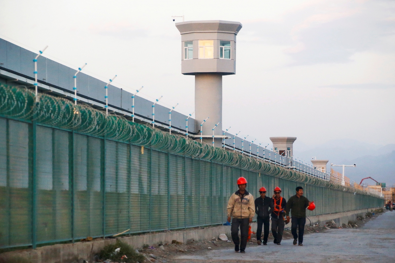 FILE PHOTO: Workers walk by the perimeter fence of what is officially known as a vocational skills education centre in Dabancheng FILE PHOTO: Workers walk by the perimeter fence of what is officially known as a vocational skills education centre in Dabancheng in Xinjiang Uighur Autonomous Region, China September 4, 2018. This centre, situated between regional capital Urumqi and tourist spot Turpan, is among the largest known ones, and was still undergoing extensive construction and expansion at the time the photo was taken. Picture taken September 4, 2018. REUTERS/Thomas Peter/File Photo Thomas Peter