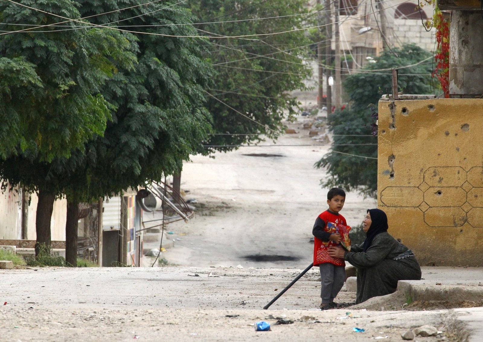 An elderly woman and a child are seen along a deserted street in the town of Ras al-Ain An elderly woman and a child are seen along a deserted street in the town of Ras al-Ain, Syria October 24, 2019. REUTERS/Aboud Hamam ABOUD HAMAM