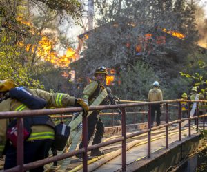 epa07958899 Firefighters navigate across a narrow bridge to battle a house fire along Hwy 128, as spot fires from the Kincade Fire erupt behind the main fire lines as a wind event starts to ramps up for the evening in Sonoma County, California, USA, 29 October 2019. The Kincade Fire has burned 75 thousand acres, destroyed over 90 buildings and is only 15 percent contained.  EPA/PETER DASILVA