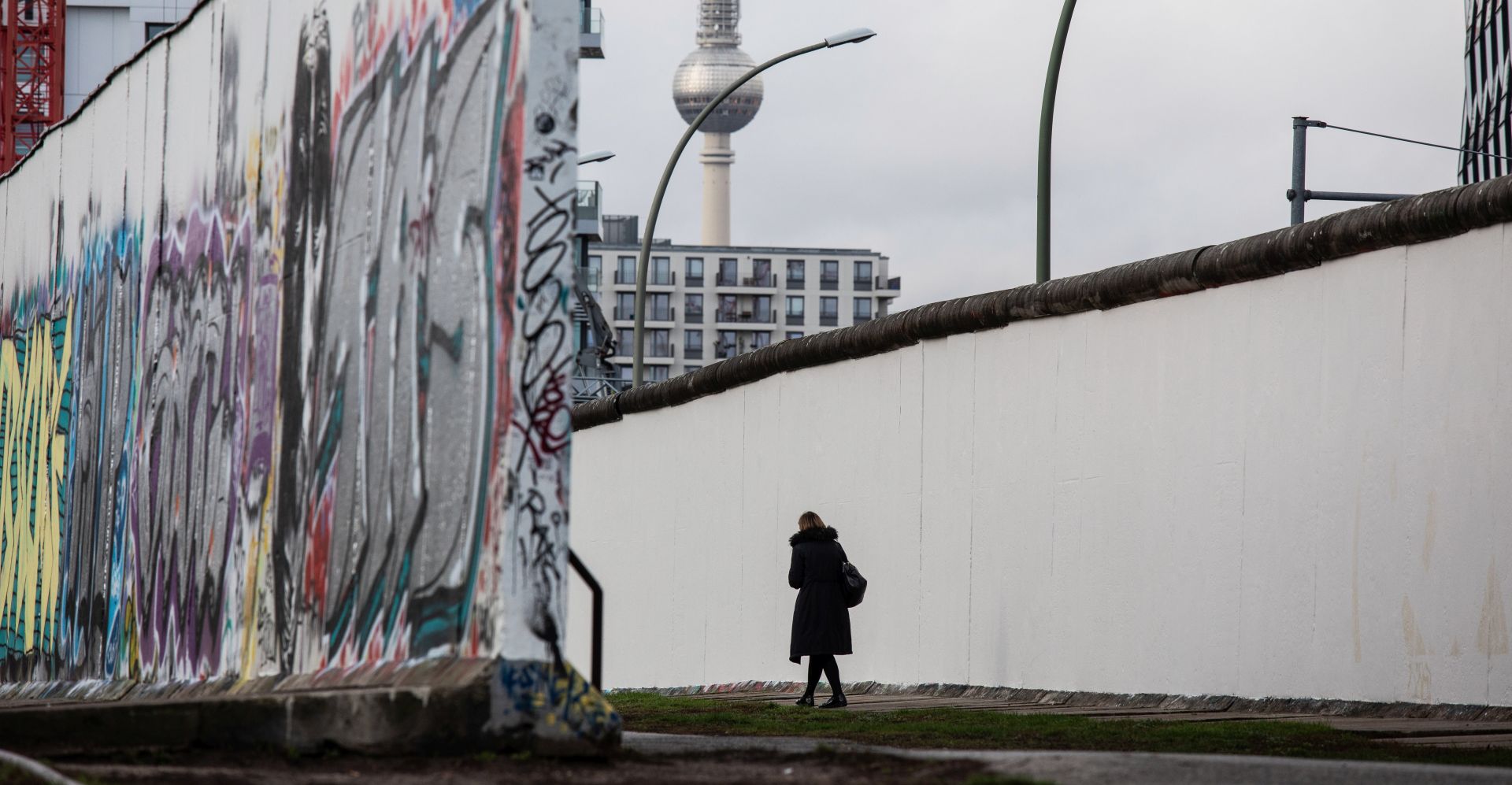 epa07972058 A visitor walks along a remaining section of the notorious Berlin Wall at the East Side Gallery in Berlin, Germany, 04 November 2019. The now German capital prepares for the celebrations marking the 30th anniversary of the fall of the Berlin Wall on 09 November 2019. Seen in background is the landmark TV tower at the Alex Square, in the former eastern part of the city.  EPA/OMER MESSINGER