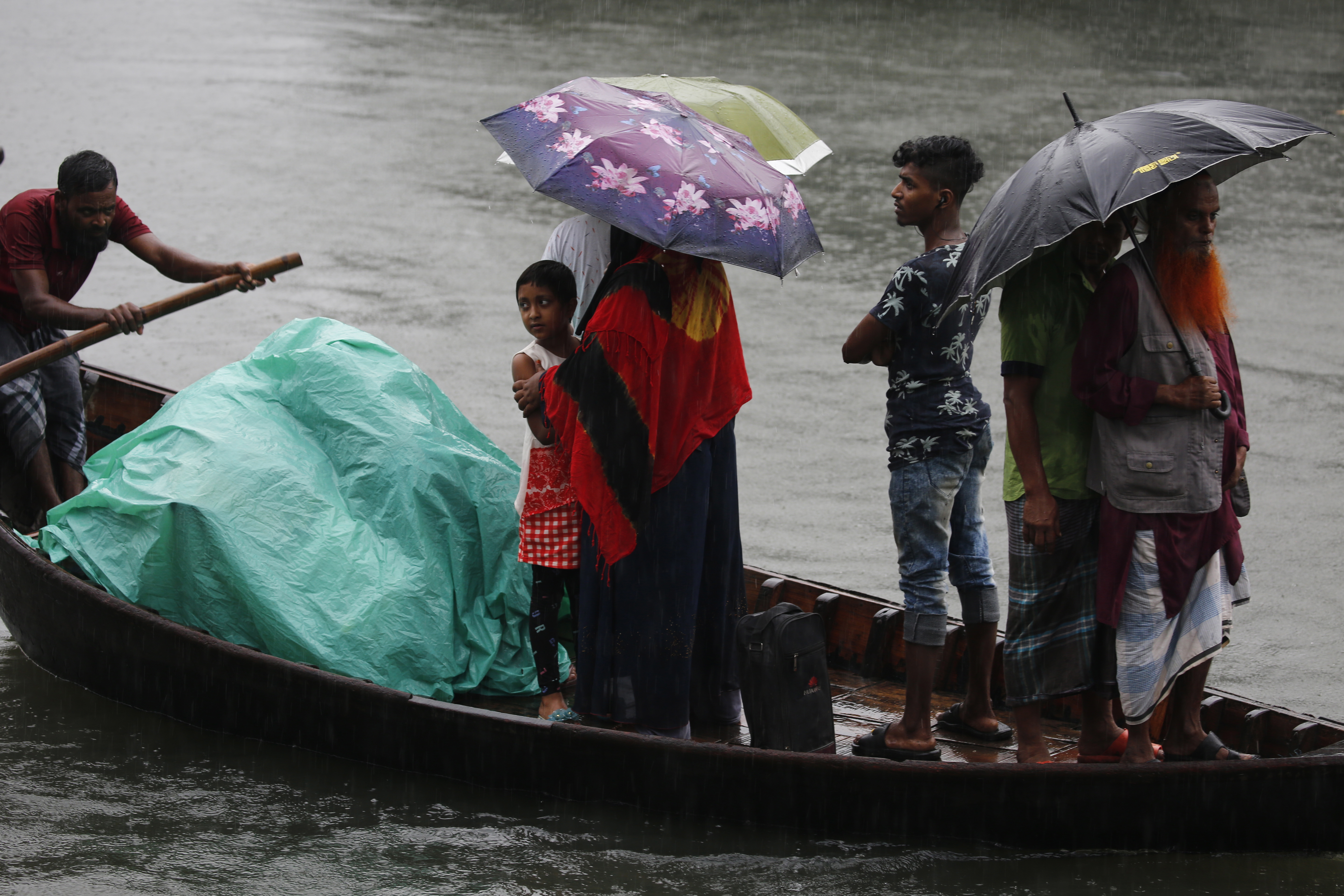 epa07983072 Bangladeshi passengers cover themselves with a plastic sheet and umbrellas as they cross the Buriganga River by boat during a rainy day in Dhaka, Bangladesh, 09 November 2019. According to the Bangladesh Inland Water Transport Authority (BIWTA) and Bangladesh Meteorology Department, the suspended inland water transport in approaching of Cyclone Bulbul, after the cyclone made landfall in the world's largest mangrove forest Sundarbans and passes through the coastal areas in Khulna and West Bengal state.  EPA/MONIRUL ALAM