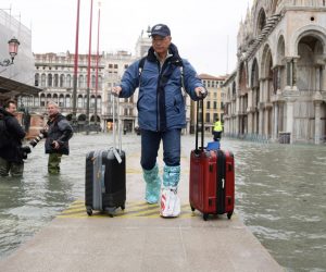 epa07998713 A tourist navigates amid high water in Venice, northern Italy, 15 November 2019. Venice is to close St Mark's Square due to fresh flooding in the city. The city is currently suffering its second-worst floods on record, with the high-water mark reaching 187cm on Tuesday. The water level had dropped down significantly but it is forecast to go back up to 160cm on today.  EPA/ANDREA MEROLA