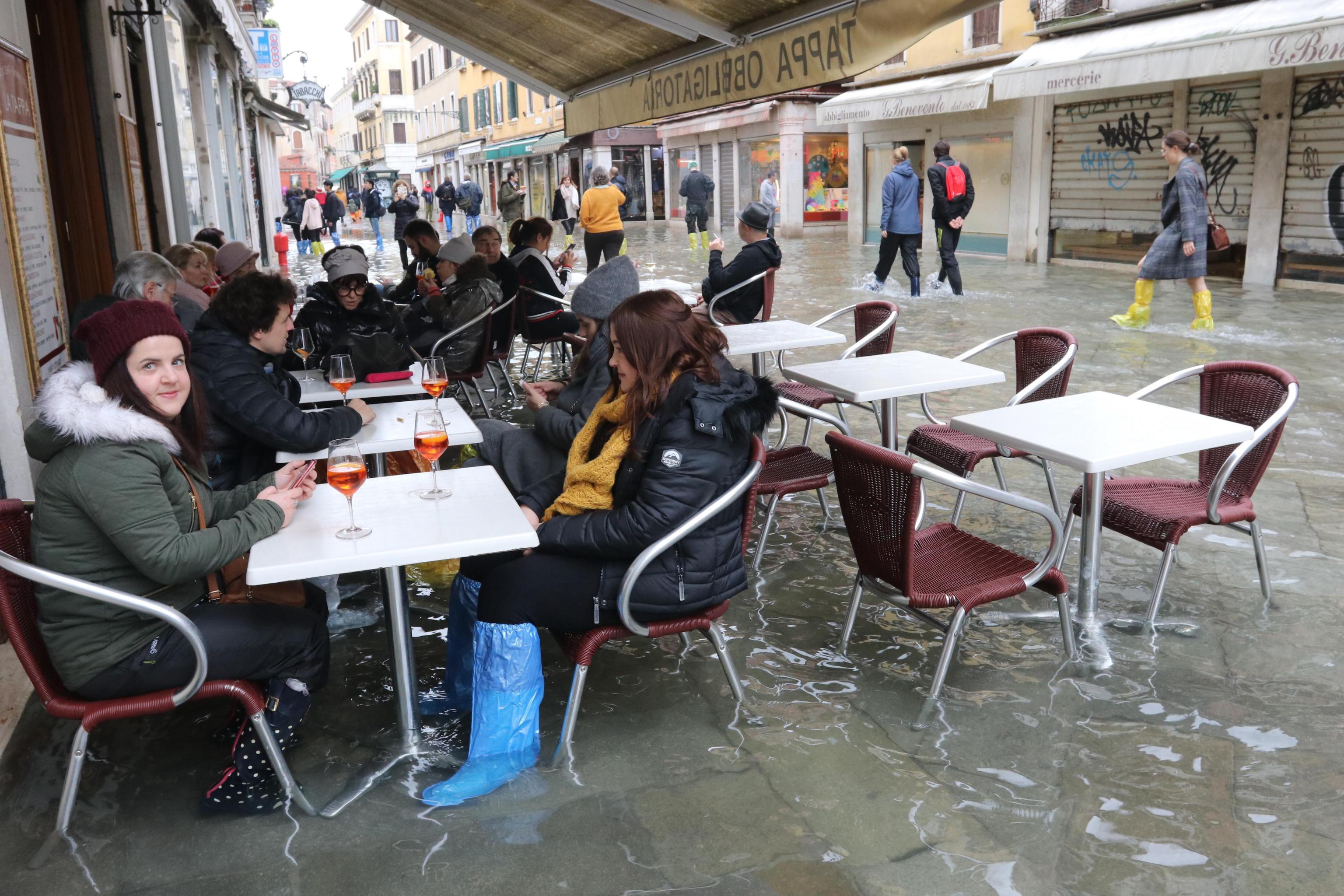 epa08003604 Tourists and residents resume their normal routine despite persistent flooding in Venice, Italy, 17 November 2019. High tidal waters returned to Venice on Saturday, four days after the city experienced its worst flooding in more than 50 years.  EPA/EMILIANO CRESPI