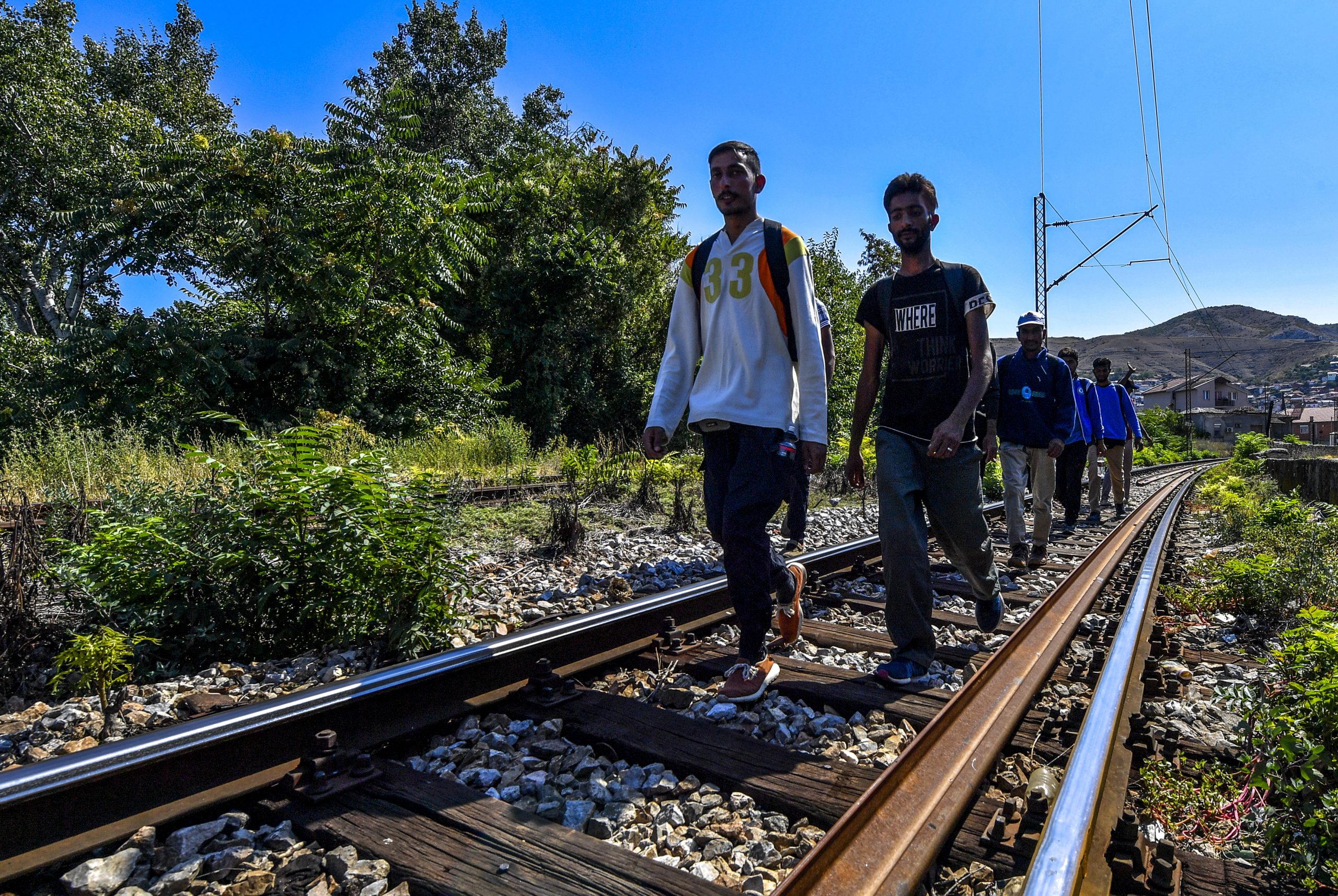 epa08046467 Undocumented migrants walk on the rail tracks during their journey towards western Europe, after resting at Lenche Zdravkin's house in Veles, Republic of North Macedonia on 14 August 2019 (issued on 05 December 2019). Lenche Zdravkin has welcomed thousands of refugees and migrants who have passed through North Macedonia on their route towards western Europe. At her home in Veles, located on a train line that the migrants use to guide their path, the travelers can find shelter, food and water, as well as a place to rest and recover before continuing their arduous journey. But perhaps most importantly, they find warmth and sympathy from a kind stranger. 'I see my children in all of the boys that come to my home,' Lenche says, who is also known by migrants as 'Mother Lenche', the 'Woman of the Railways'and 'Angel of the Refugees'.  EPA/GEORGI LICOVSKI  ATTENTION: This Image is part of a PHOTO SET