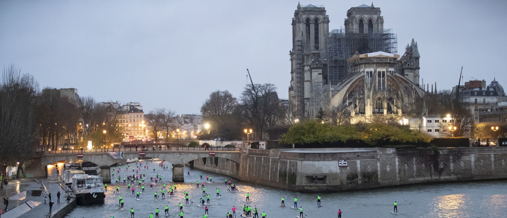 epa08054215 Amateur and professional paddleboarders pass by Notre-Dame Cathedral as they take part in a paddle board race on the Seine river in Paris, France, 08 December 2019. Over 1,000 participants took part, paddling along 11 kilometers on the Seine river.  EPA/IAN LANGSDON