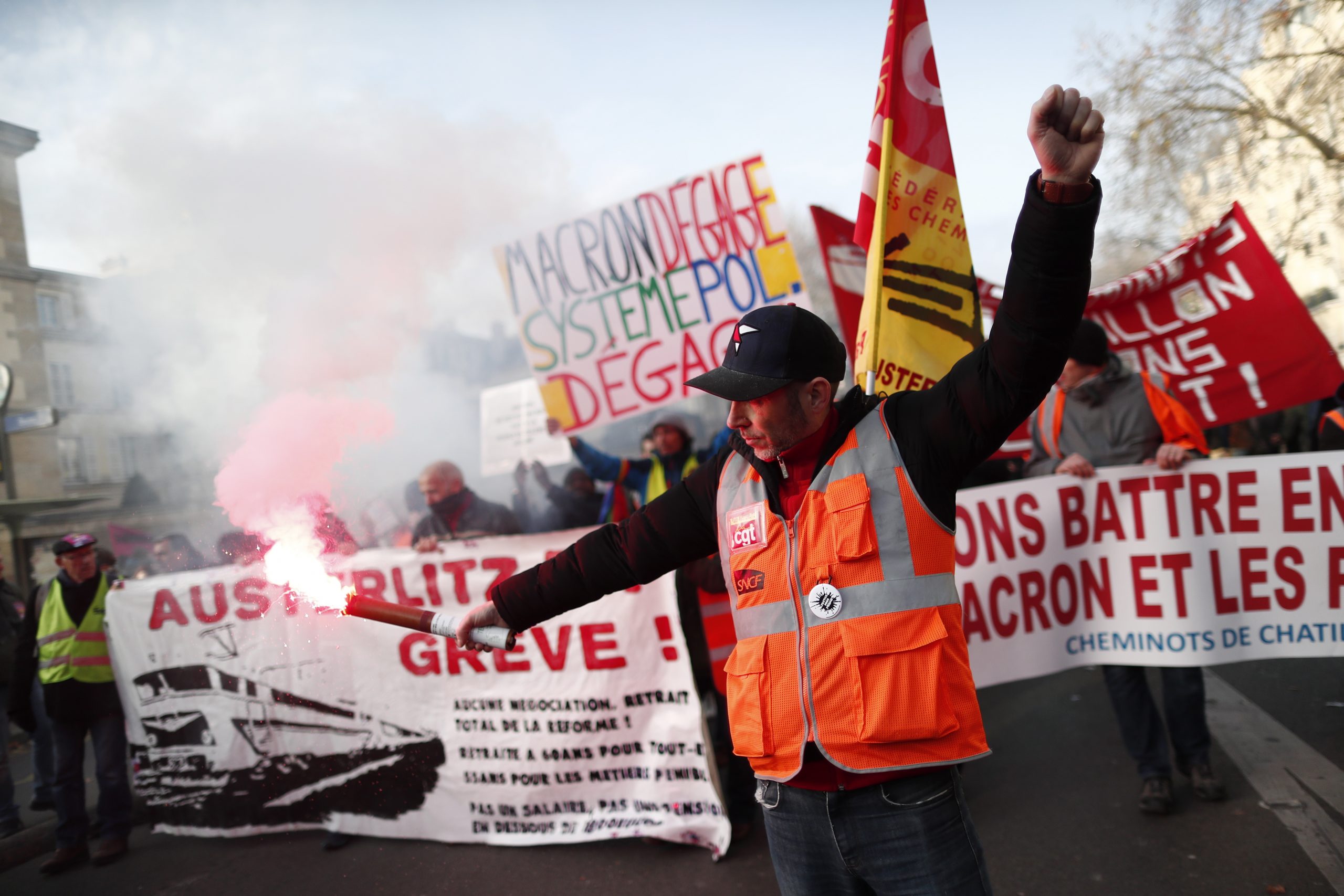 epa08059975 A protestor lights a flare as he participates in a demonstration against pension reforms in Paris, France, 10 December 2019. French unions representing railway and transport workers and many others in the public sector called for a general strike and demonstrations to protest against the French government's reform of the pension system which is planned to be announced on 11 December.  EPA/IAN LANGSDON
