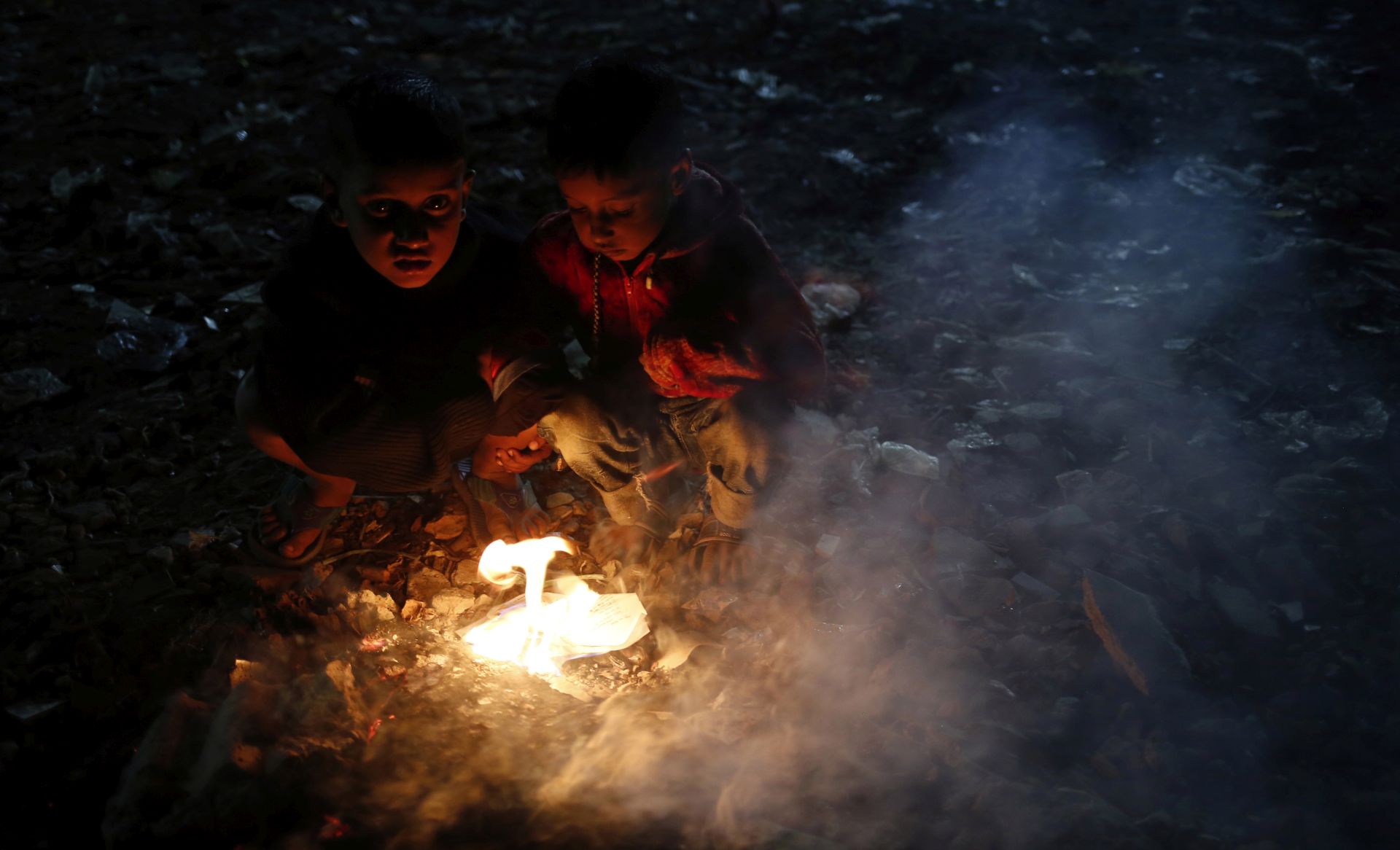 epa08083852 Bangladesh children to keep warm themselves by setting rubbish on fire at night during a cold wave grips in Dhaka, Bangladesh 20 December 2019. According to the Met office a mild cold wave sweeping across the county in Bangladesh.  EPA/MONIRUL ALAM
