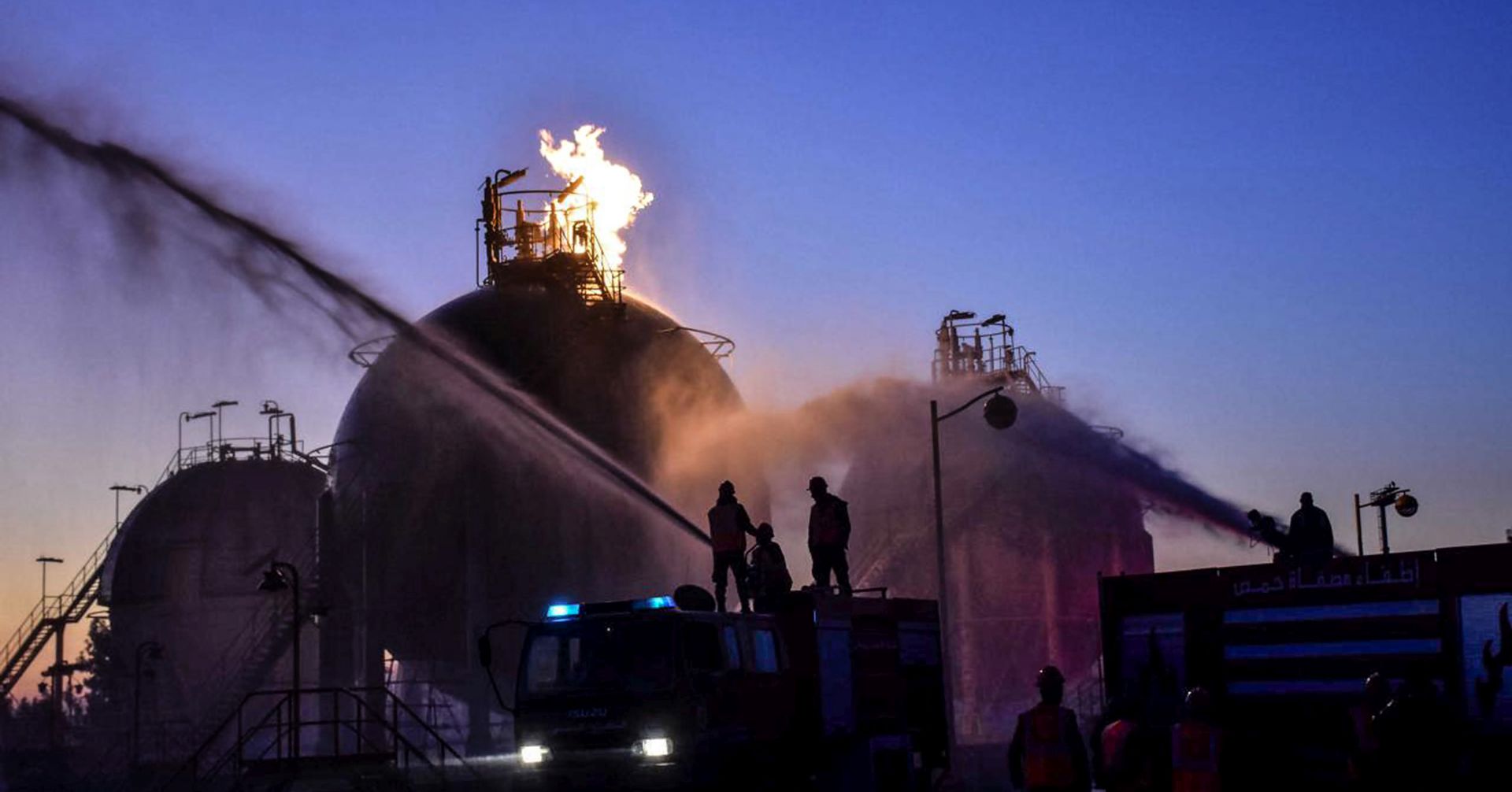 epa08084623 A handout photo made available by the official Syrian Arab News Agency (SANA) shows firefighters extinguishing a fire at the Homs refinery, Homs governorate, Syria, 21 December 2019. According to SANA, the Homs refinery, Gas factory of southern Central region and al-Rayan Gas station came under 'terrorist synchronous attacks' causing damage in the production units.  EPA/SANA HANDOUT  HANDOUT EDITORIAL USE ONLY/NO SALES