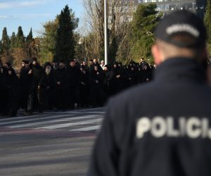 epa08088794 A police officer keeps watch as Serbian Orthodox Church priests and nuns in Montenegro take part in a protest rally in Podgorica, Montenegro, 24 December 2019. The Serbian Orthodox Church in Montenegro is protesting against a controversial new law on religion, which the church has called a plot to rob it of its property. Montenegro's government proposed a new bill on religion requiring all religious communities, including Catholic and Orthodox churches, to register their immovable assets as state property. The law also states that religious communities can only retain their assets if they can produce evidence of the right to ownership, triggering allegations from the Serbian Church that the government plans to dispute its holdings.  EPA/BORIS PEJOVIC