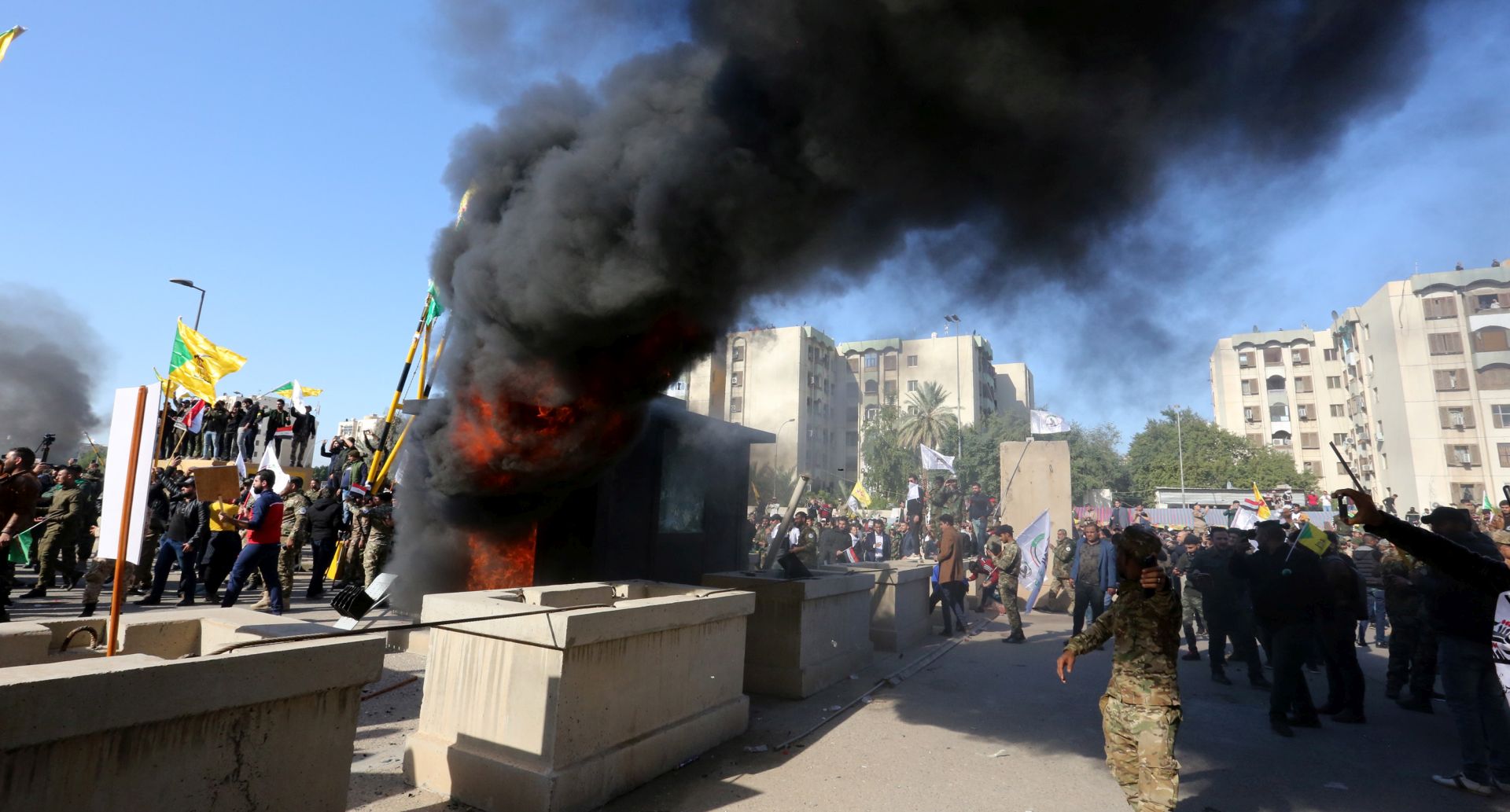 epa08096524 Members of Iraqi Shiite 'Popular Mobilization Forces' armed group and their supporters attack the US Embassy as as smoke rises from its entrance in Baghdad, Iraq, 31 December 2019. According to media reports, the US ambassador and other members of the staff were evacuated as dozens of people broke into the embassy's compound after setting fire to the reception area. The attack at the embassy follows a deadly US airstrike that killed 25 fighters of the Iran-backed militia on 29 December.  EPA/AHMED JALIL