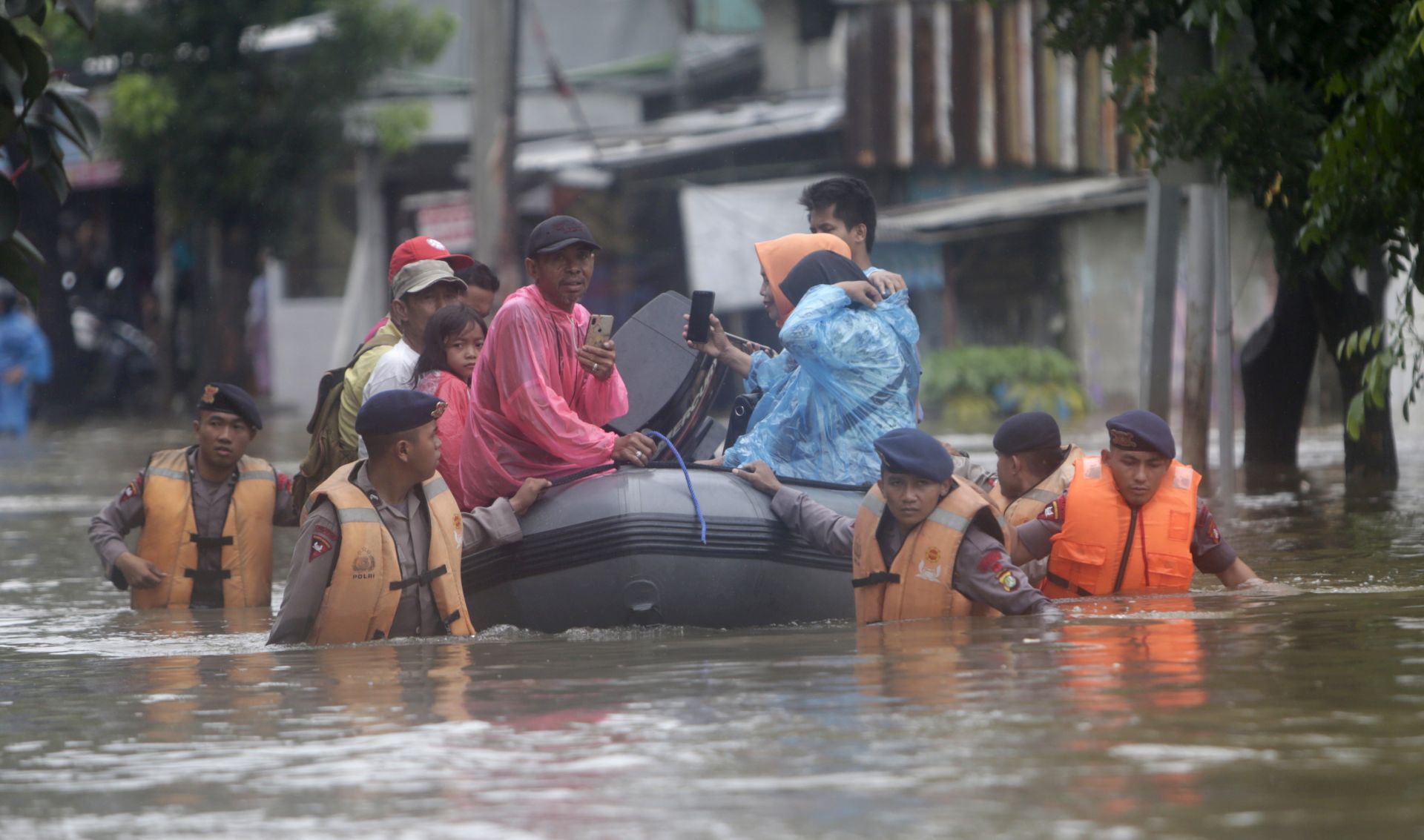 epa08097177 Indonesian police pull a rubber dinghy as they evacuate residents in Jakarta, Indonesia, 01 January 2020. Overnight heavy rains triggered widespread flooding in Jakarta and surrounding areas, bringing traffic to a standstill.  EPA/ADI WEDA