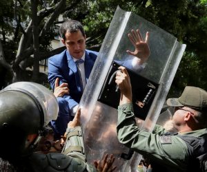 epa08105248 Venezuelan opposition leader Juan Guaido climbs a fence in an attempt to enter the headquarters of the National Assembly, guarded by the police to prevent his entry and that of opposition deputies in Caracas, Venezuela, 05 January 2020. Chavista deputies of the National Assembly (AN, Parliament) elected Luis Parra, former member of the First Justice party, as President of the Parliament, in a brief debate that opposition leader and now former president of the Parliament Juan Guaido did not attend as he was held for hours by the Police around the Legislative Palace. Before the session, troops of the Bolivarian National Police (GNP) and the Bolivarian National Guard (GNB, militarized police), prevented Guaido and other deputies access to Parliament.  EPA/Rayner Pena