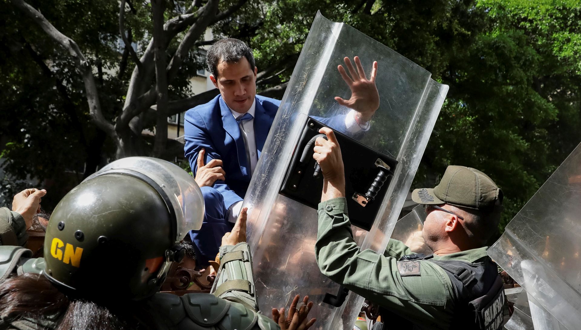 epa08105248 Venezuelan opposition leader Juan Guaido climbs a fence in an attempt to enter the headquarters of the National Assembly, guarded by the police to prevent his entry and that of opposition deputies in Caracas, Venezuela, 05 January 2020. Chavista deputies of the National Assembly (AN, Parliament) elected Luis Parra, former member of the First Justice party, as President of the Parliament, in a brief debate that opposition leader and now former president of the Parliament Juan Guaido did not attend as he was held for hours by the Police around the Legislative Palace. Before the session, troops of the Bolivarian National Police (GNP) and the Bolivarian National Guard (GNB, militarized police), prevented Guaido and other deputies access to Parliament.  EPA/Rayner Pena