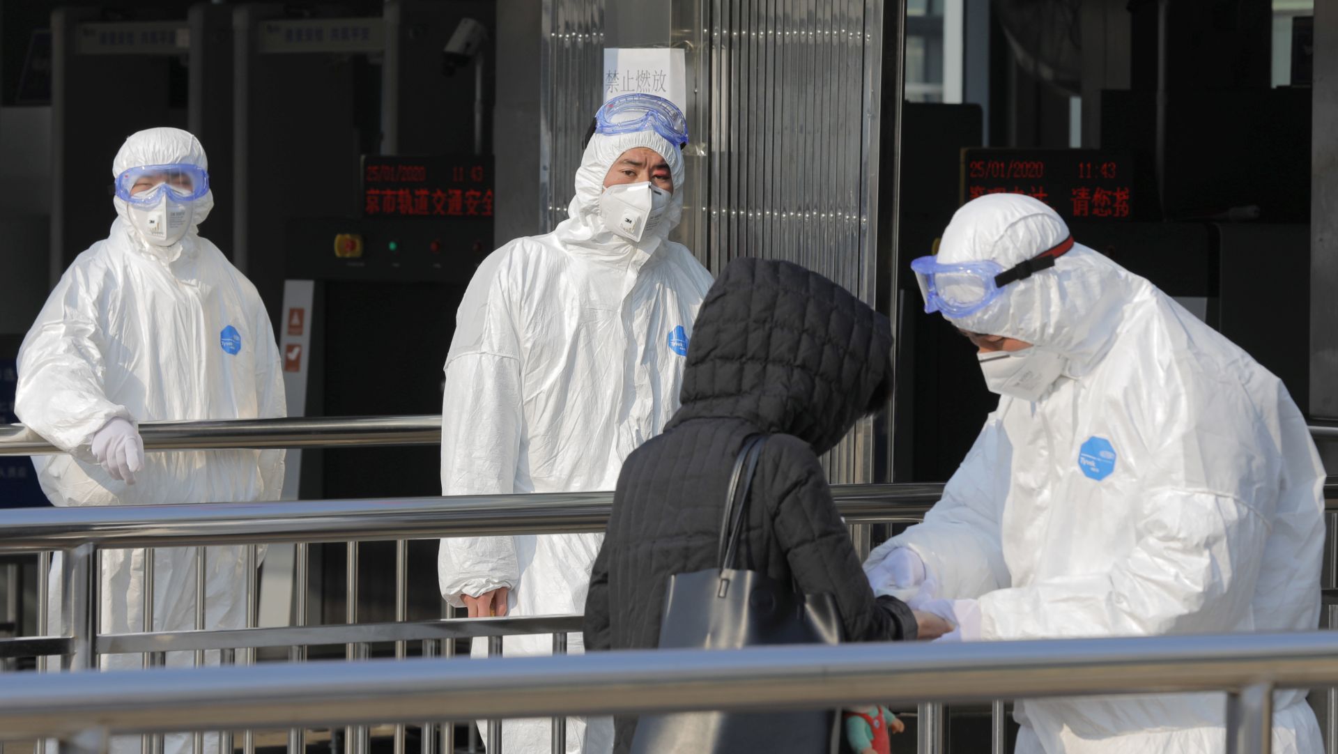 epa08161528 Security personnel wearing hazardous material suits measure body temperatures of passenger at the entrance of a subway station in Beijing, China, 25 January 2020. Two airports in Beijing will start to measure temperatures for arriving passengers from 25 January 2020 as the outbreak of coronavirus has so far claimed 41 lives and infected about 1300 others, according to media reports.  EPA/WU HONG